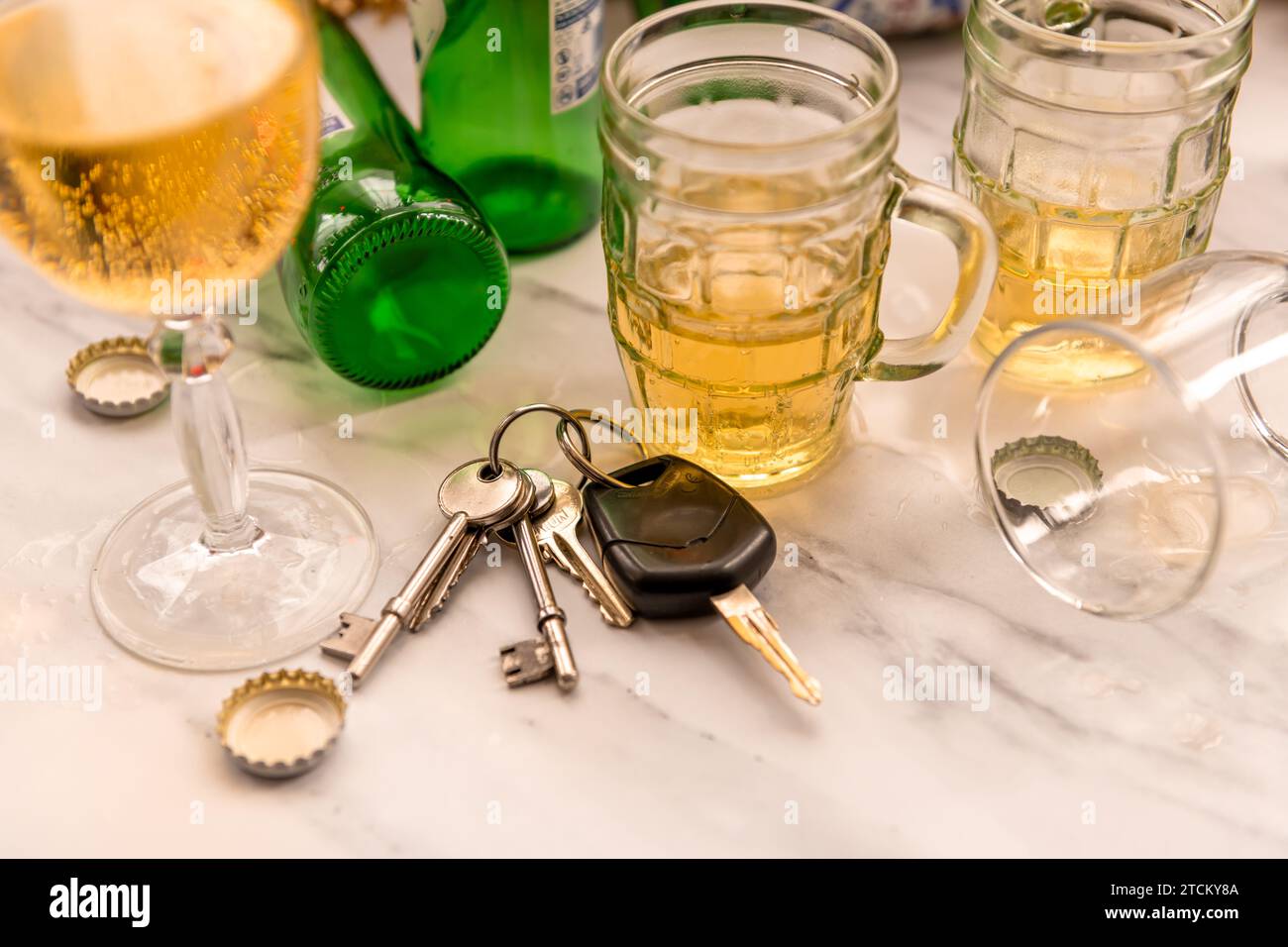 Ein Satz Autoschlüssel auf einem Tisch voller Gläser mit alkoholischen Getränken und Flaschen. Getränk Fahrkonzept. Stockfoto