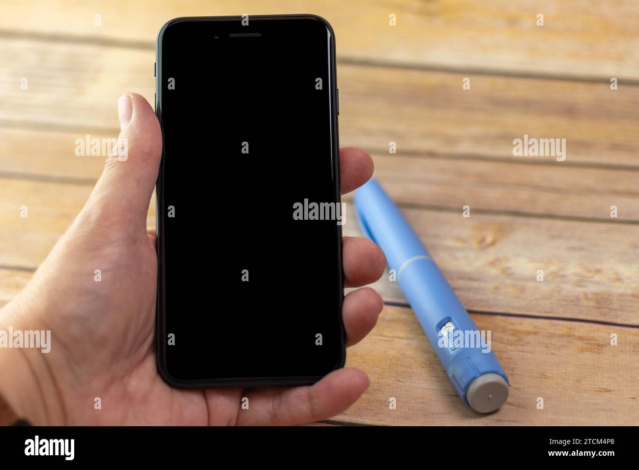 Ein mobiles Handgerät mit Semaglutid-Stift im Hintergrund Stockfoto