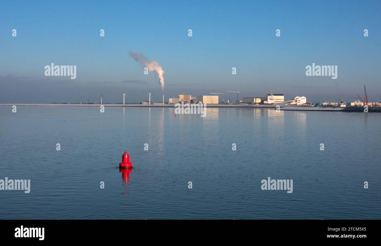 Industriegebiet an der Küste, vom Meer aus gesehen. Im Vordergrund eine rote Boje. Stockfoto