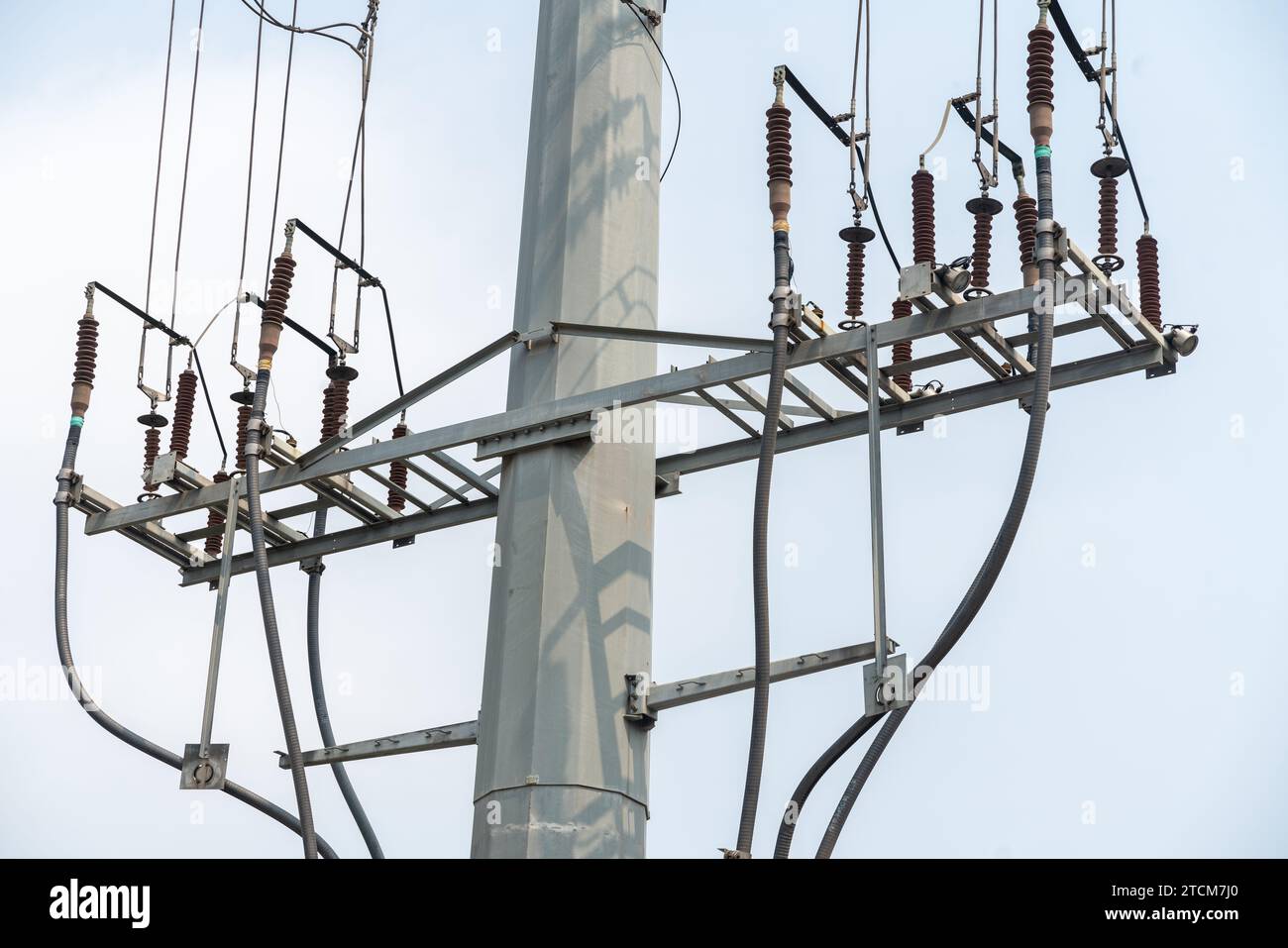 Diese Abbildung zeigt eine Nahaufnahme eines elektrischen Pfostens mit mehreren Kabeln, die davon abhängen, und einem Lichtmast Stockfoto