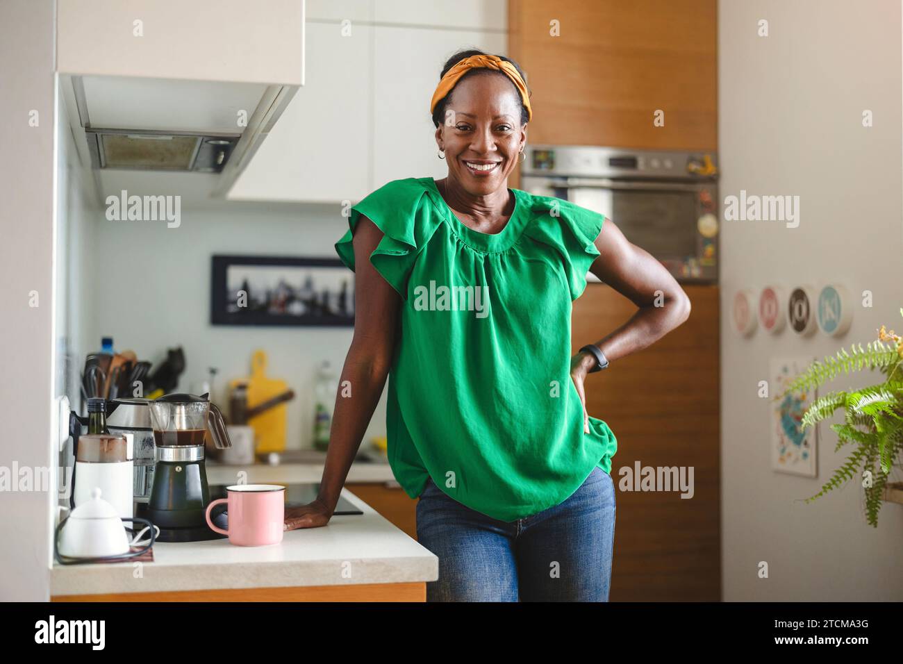 Porträt einer lächelnden Reifen Frau, die in ihrer Küche steht Stockfoto