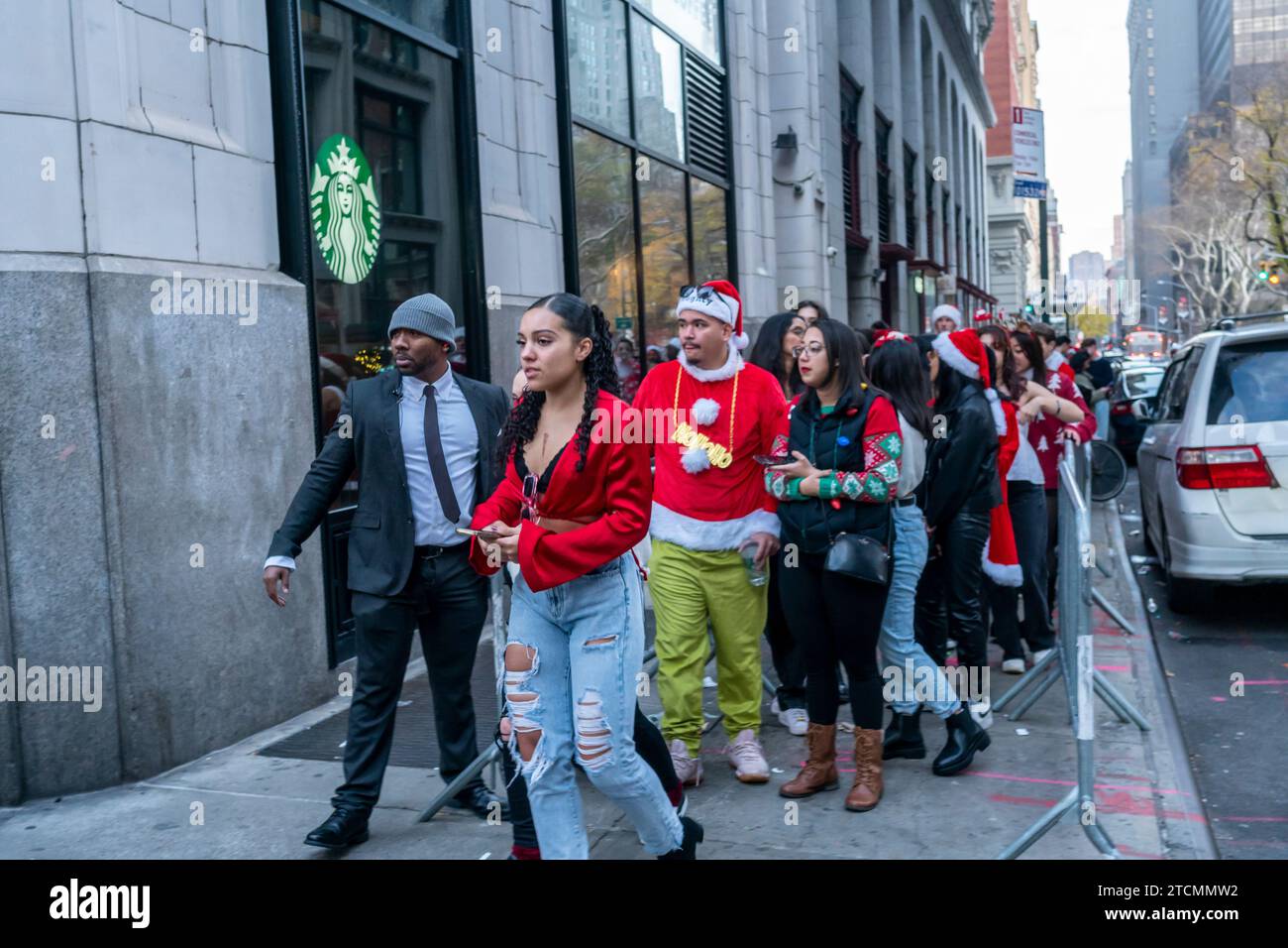 Hunderte von Santas, begleitet von ihren Helfern und einigen frechen Elfen, warten online, um die Smith Bar im Nomad-Viertel in Manhattan in New York während des jährlichen Kneipenbummels SantaCon am Samstag, den 19. Dezember 2023, zu betreten. Die SantaCon, in erster Linie ein Kneipenbummel in Weihnachtskostümen und anderen Weihnachtskostümen, zieht Maskierer an, die von Bar zu Bar gehen. (© Richard B. Levine) Stockfoto