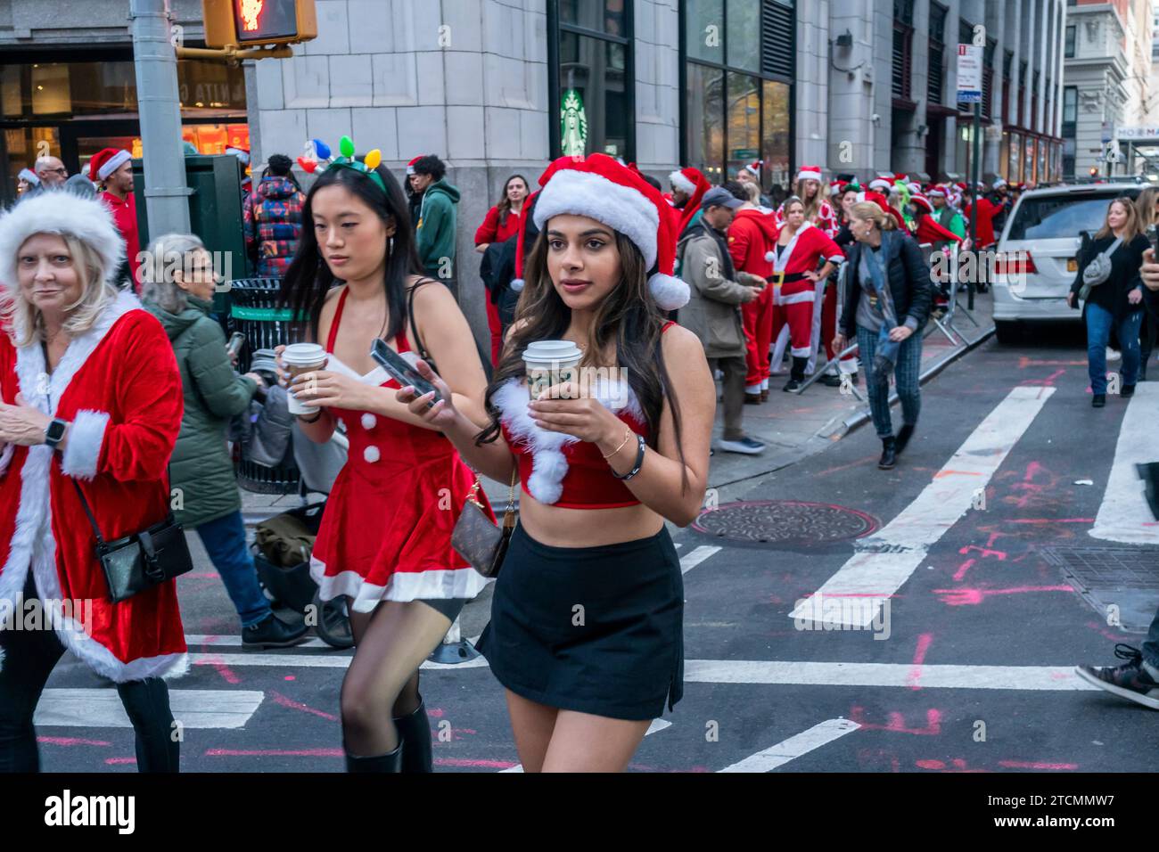 Hunderte von Santas, begleitet von ihren Helfern und einigen frechen Elfen, warten online, um die Smith Bar im Nomad-Viertel in Manhattan in New York während des jährlichen Kneipenbummels SantaCon am Samstag, den 19. Dezember 2023, zu betreten. Die SantaCon, in erster Linie ein Kneipenbummel in Weihnachtskostümen und anderen Weihnachtskostümen, zieht Maskierer an, die von Bar zu Bar gehen. (© Richard B. Levine) Stockfoto