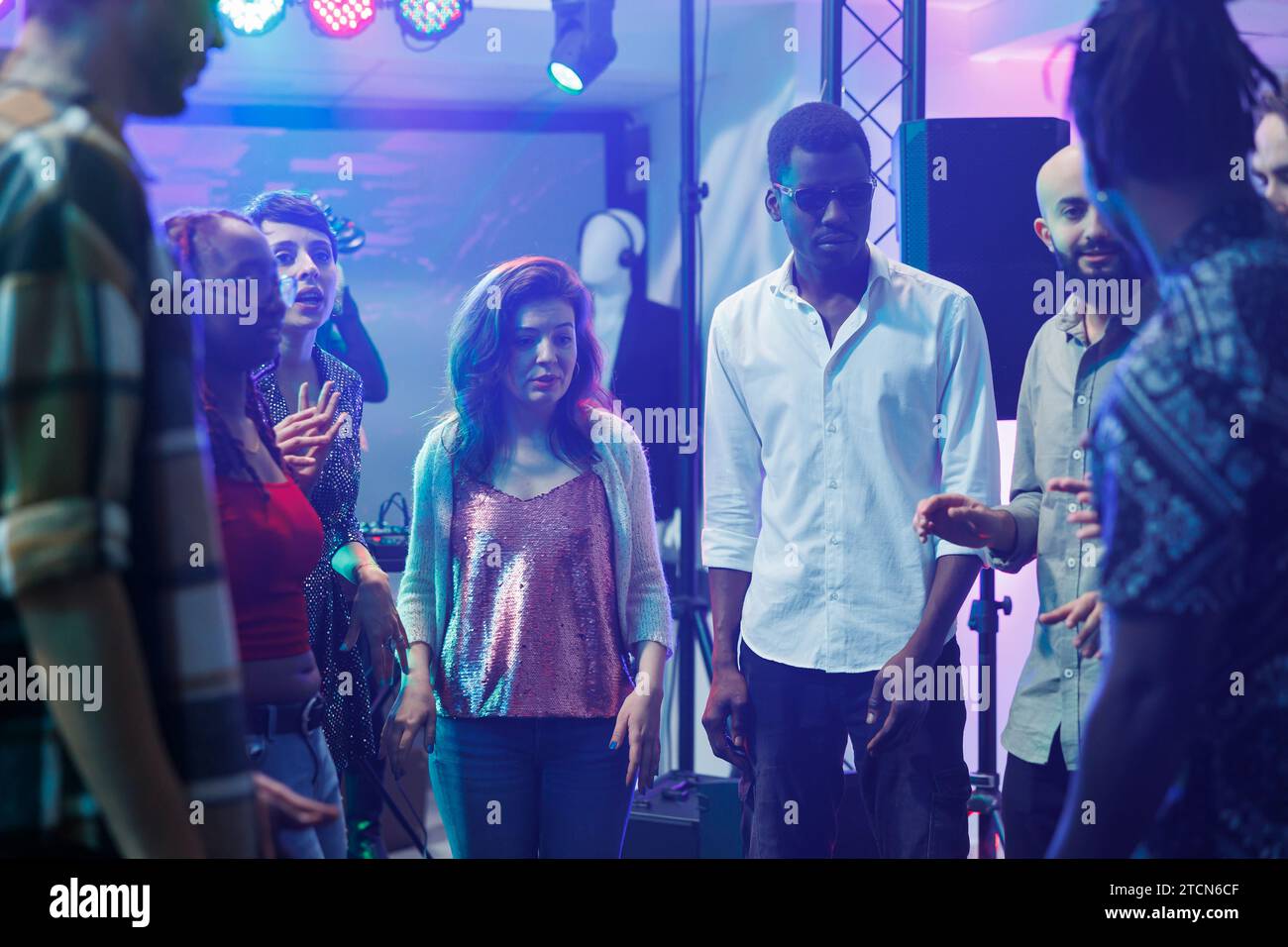 Junge Freunde unterhalten sich während einer Party auf der Tanzfläche und improvisieren Tanzkämpfe in einem überfüllten Nachtclub. Verschiedene Leute, die Spaß haben und sich unterhalten, während sie im Club spielen und feiern Stockfoto