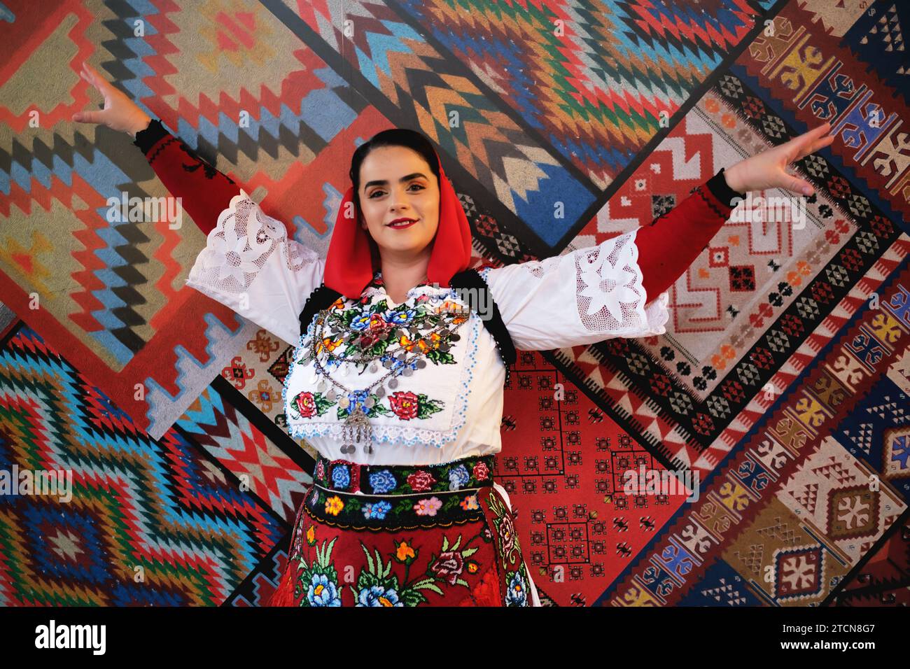 Tirana, Albanien - 28. November: Eine Frau in albanischer Kleidung posiert allein vor einem Hintergrund mit traditionellen albanischen Mustern Stockfoto