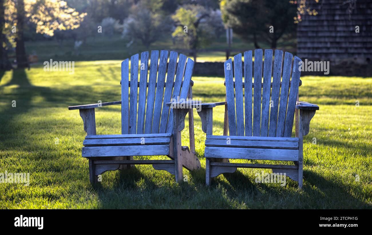 Zwei leere Adirondack Stühle in einem Yard mit unscharfem Hintergrund und traumhaftem Sonnenlicht, Tewksbury, New Jersey, USA Stockfoto