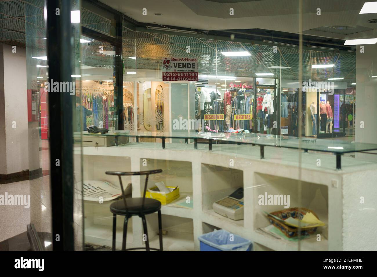 Caracas, Venezuela. Dezember 2023. Ein leeres Geschäft mit einem Schild mit der Aufschrift „zum Verkauf“ in einem Einkaufszentrum im Stadtzentrum. Nach einem kurzen Boom dank der Dollarisierung der Wirtschaft ist Venezuelas wirtschaftliche Lage mit einer jährlichen Inflation von 398 % und einem Rückgang der Wirtschaftstätigkeit um 7 % immer noch beunruhigt. Mit einem Mindestlohn von nur 8 Dollar kämpft ein Großteil der Bevölkerung immer noch darum, das Ende des Monats zu erreichen. Quelle: SOPA Images Limited/Alamy Live News Stockfoto