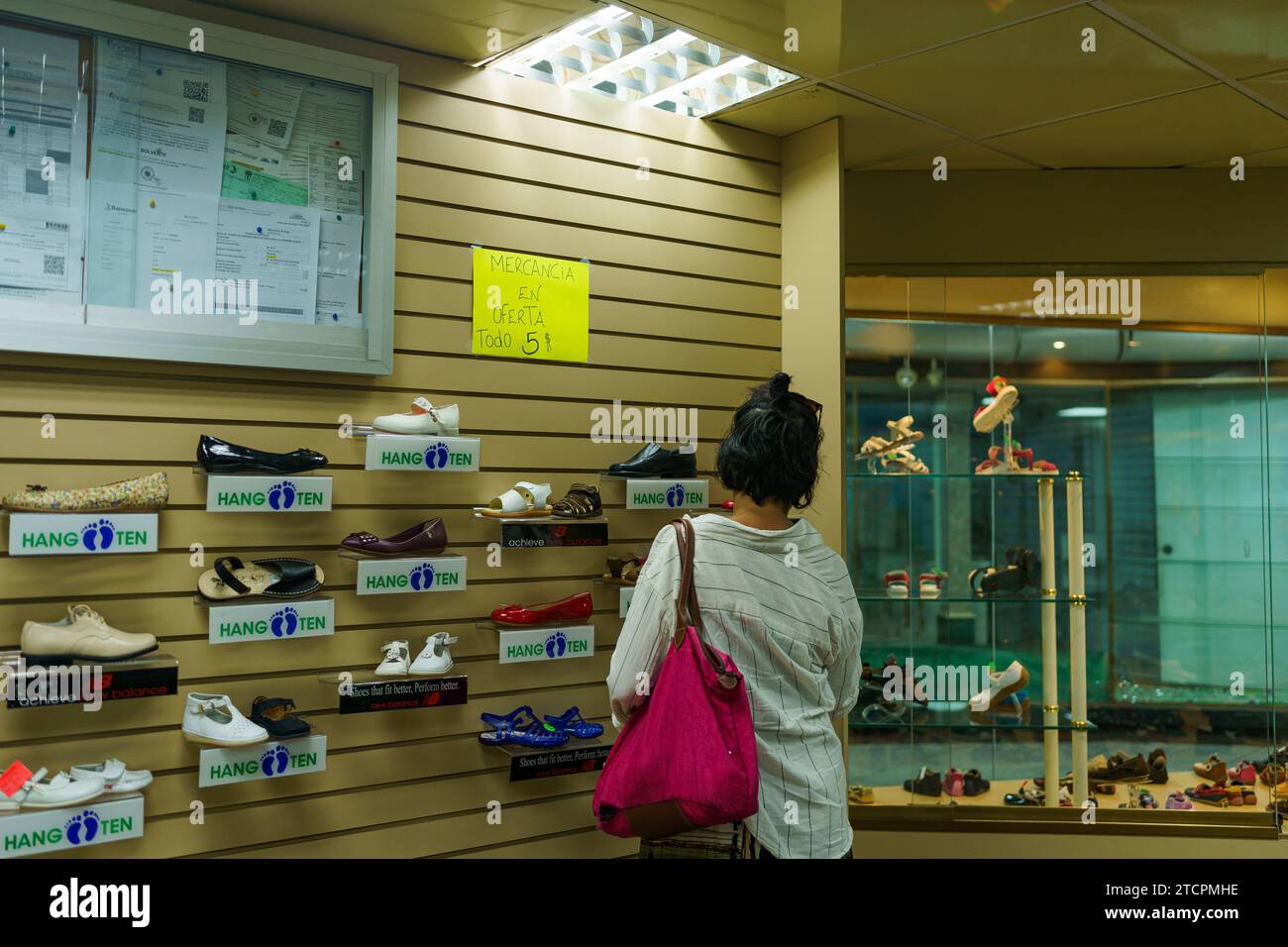 Caracas, Venezuela. Dezember 2023. Eine Frau sah in einem Schuhgeschäft im Stadtzentrum einkaufen. Nach einem kurzen Boom dank der Dollarisierung der Wirtschaft ist Venezuelas wirtschaftliche Lage mit einer jährlichen Inflation von 398 % und einem Rückgang der Wirtschaftstätigkeit um 7 % immer noch beunruhigt. Mit einem Mindestlohn von nur 8 Dollar kämpft ein Großteil der Bevölkerung immer noch darum, das Ende des Monats zu erreichen. Quelle: SOPA Images Limited/Alamy Live News Stockfoto