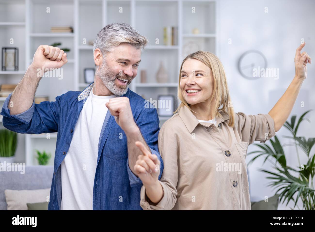 Glückliches Seniorenpaar tanzt im älteren Wohnzimmer, glücklicher Ehemann und Frau, Familienwerte. Stockfoto