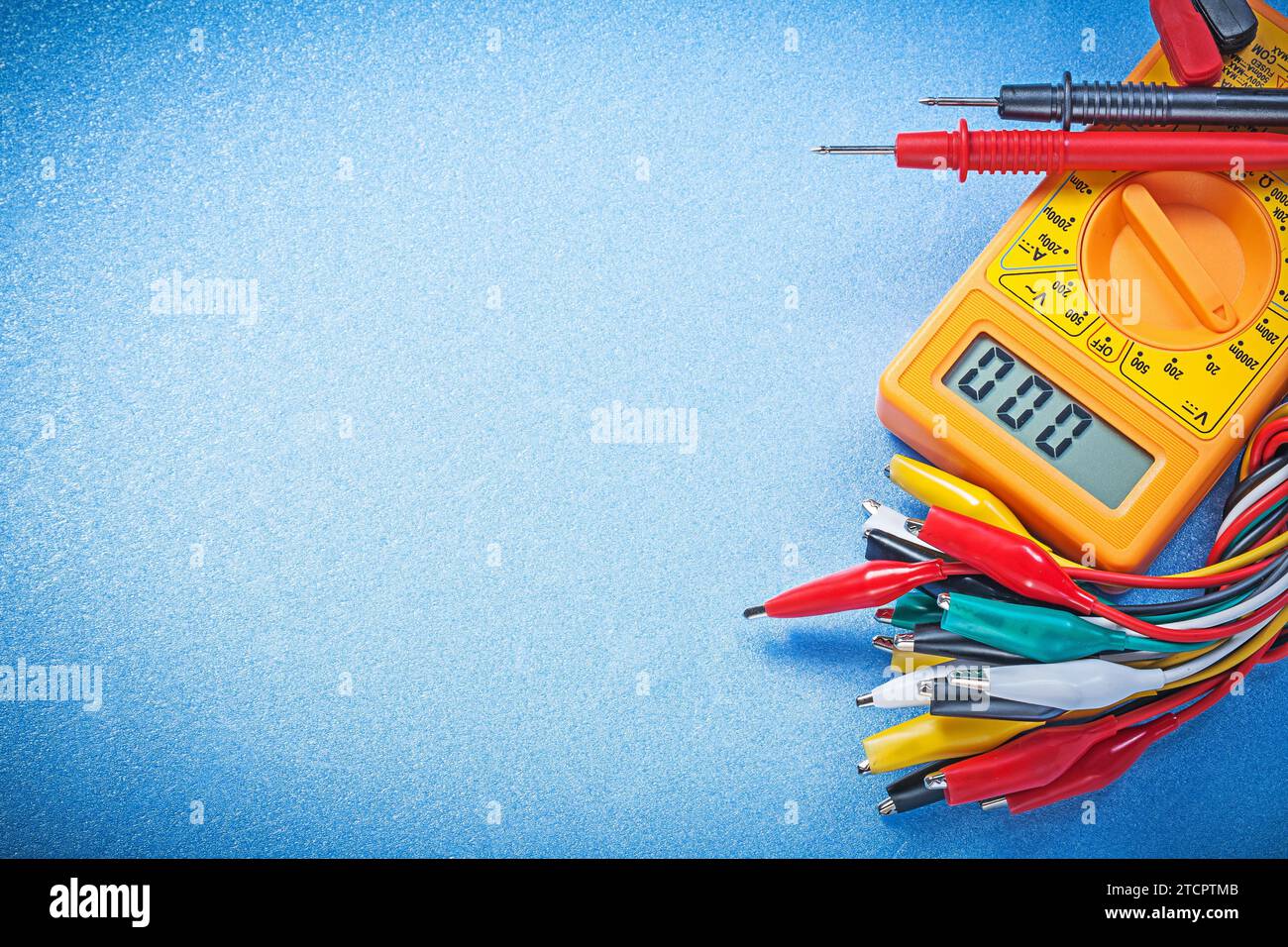 Elektrisches Digitalmultimeter mit Krokodilstecker auf blauem Hintergrundstromkonzept Stockfoto