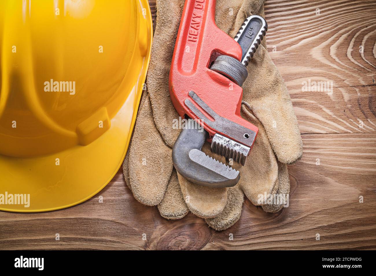 Schutzhelmschutzhandschuhe Affenschlüssel auf Holzbrettbaukonzept Stockfoto