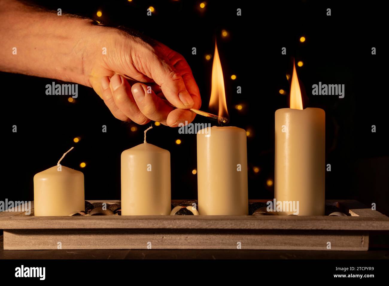 Zünde die zweite Adventskerze mit einem Streichholz an Stockfoto