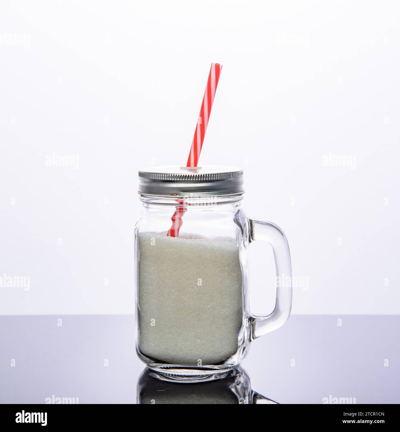 Trinken Sie Glas Glas mit rotem Stroh voller Zucker. Isoliert auf weißem Hintergrund. Konzept für Zuckergetränke Stockfoto