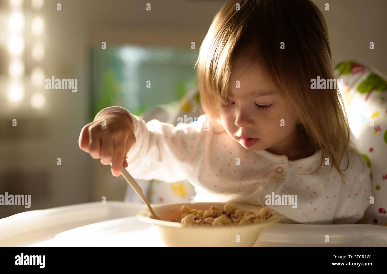 Zwei Jahre alt isst Haferbrei von sich aus mit einem Löffel. Entwicklungskonzept für Kinder Stockfoto