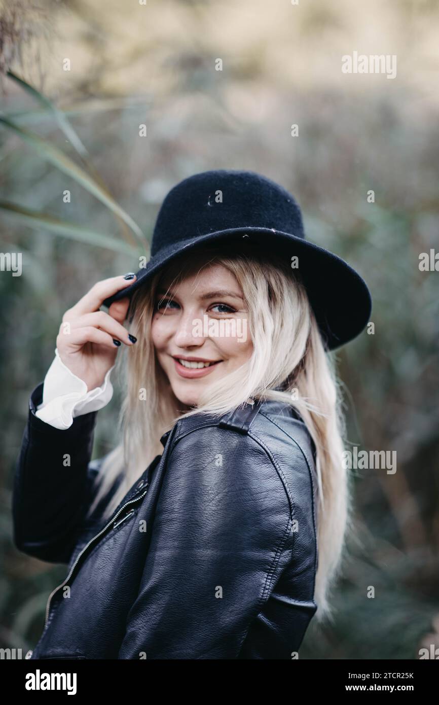 Blondes Mädchen in Lederjacke und Hut vor dem Hintergrund eines Feldes Stockfoto