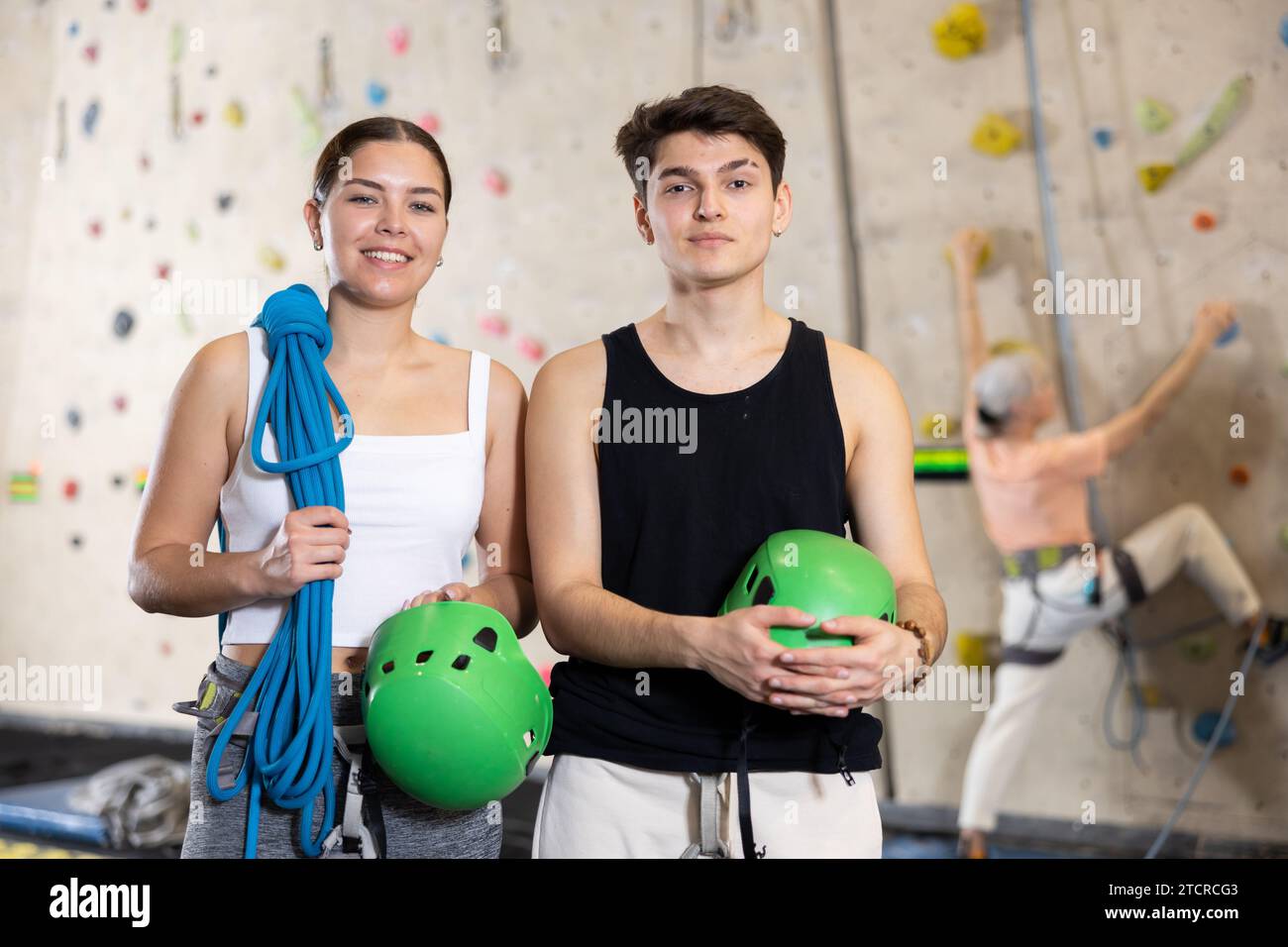 Motivierte, sportliche Jugendliche, Mann und Frau, die mit Spezialausrüstung stehen, bevor sie im Vergnügungszentrum die Boulderwand hochklettern Stockfoto