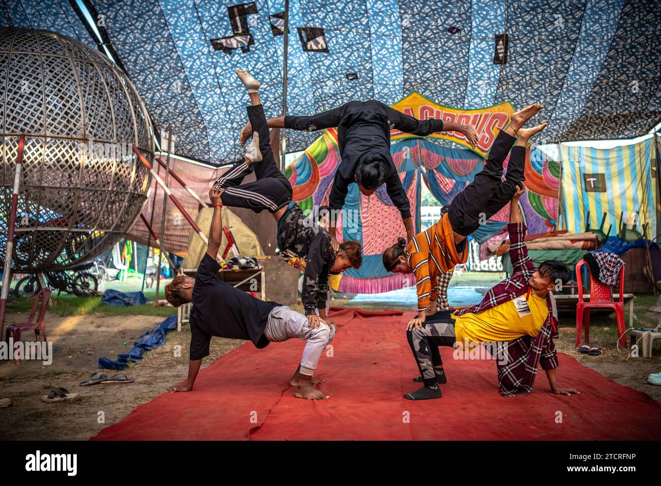 Zirkuskünstler aus Manipur üben ihre Stunts in einem Zirkuszelt vor der letzten Vorstellung. Winter und Kindheit bedeuteten eine Zeit, in der es eine besondere Anziehungskraft und Liebe für den Zirkus gab. Aber jetzt haben sich die Zeiten geändert, so dass die Nachfrage auch gesunken ist, besonders nachdem die Show von Tieren aller Art im Zirkus aufgehört hat, sind die Besitzer der Zirkusteams verärgert. Jetzt wird das Spiel nur mit Jokern oder Leuten gezeigt. Und das Ergebnis ist, dass das Einkommen gesunken ist. Jetzt haben sogar die Kleinen das Interesse am Zirkus verloren. Infolgedessen ist das Einkommen des Zirkus gesunken Stockfoto