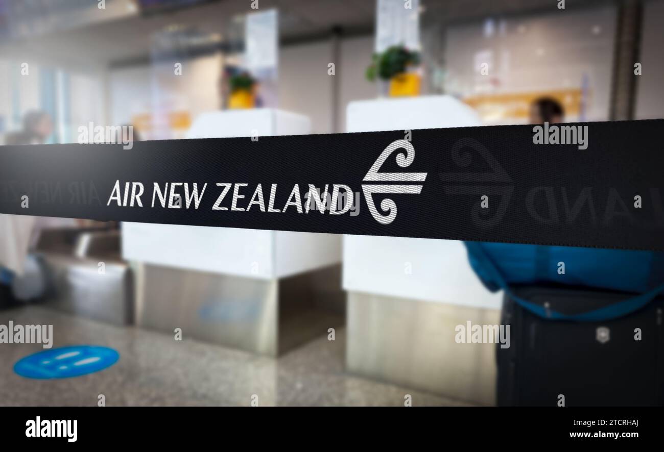 Auckland, NZ, 4. Dezember 2023: Ein Air New Zealand-Band hebt sich an einem geschäftigen Flughafenschalter hervor und deutet auf die Spannung der bevorstehenden Reisen hin Stockfoto