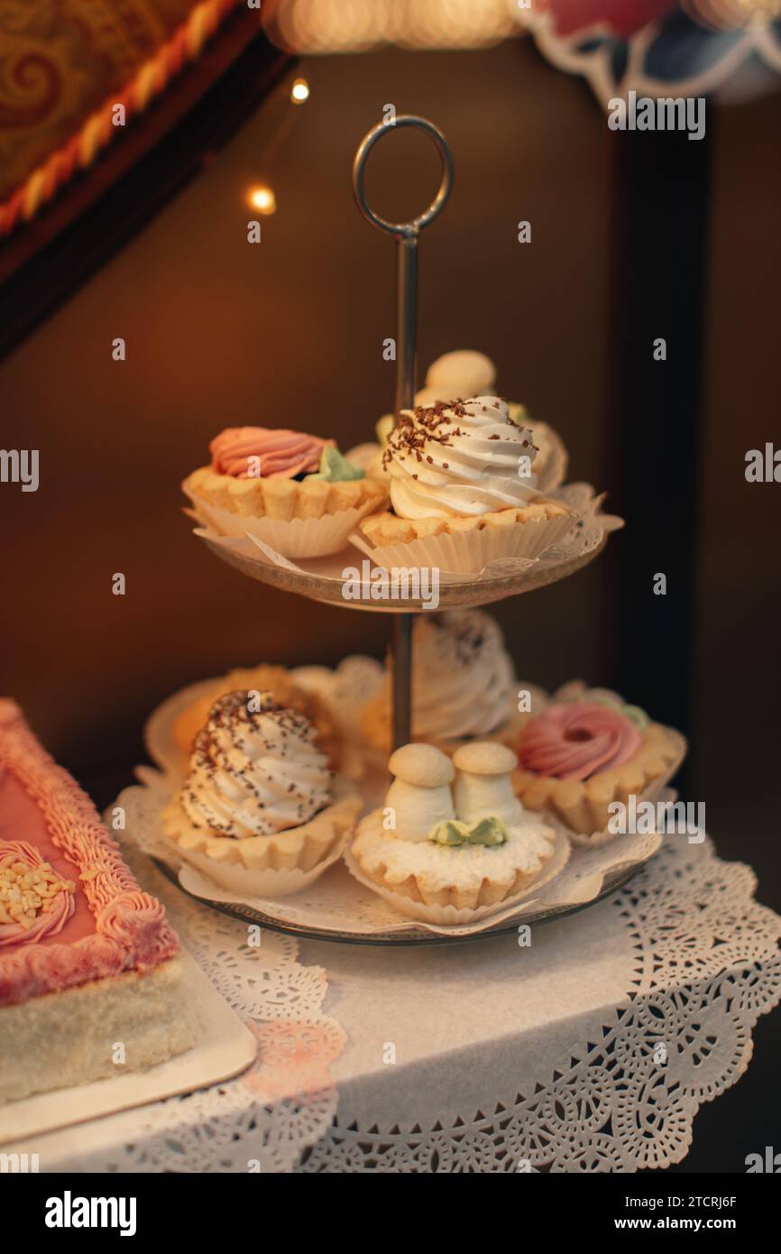 Süße Kuchenkörbe mit flauschiger Creme auf einem zweistöckigen Ständer Stockfoto