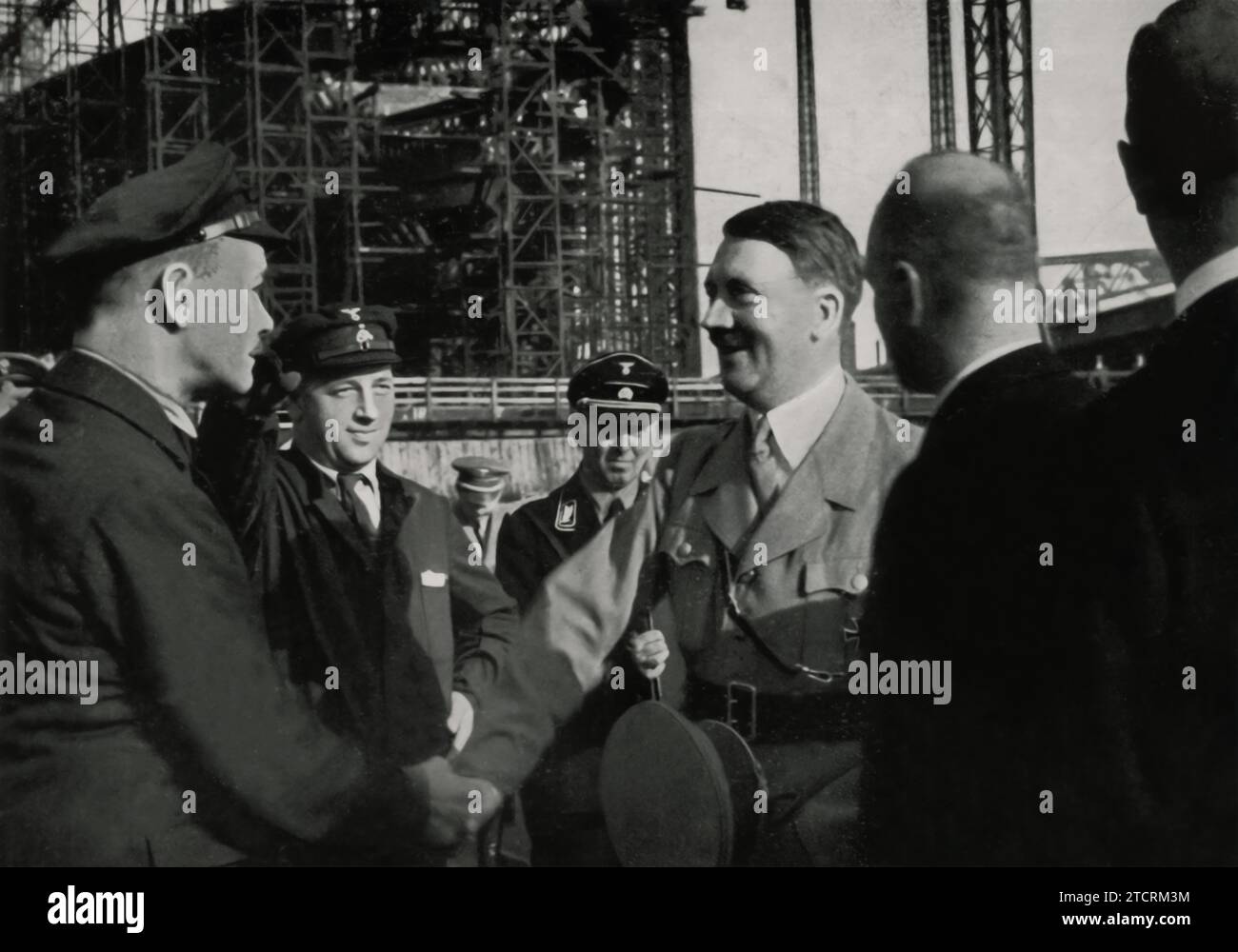 Adolf Hitlers Besuch auf der Werft Blohm & Voss im Jahr 1934 unterstreicht das Engagement des NS-Regimes für die Stärkung der Kriegsmarine. Dieser Rundgang durch eine wichtige Marinebaustelle zeigt die strategische Bedeutung der Seemacht und die für eine gewaltige Marinestreitkraft notwendige industrielle Kapazität, die mit den umfassenderen Militarisierungsbemühungen Deutschlands in Einklang steht. Stockfoto