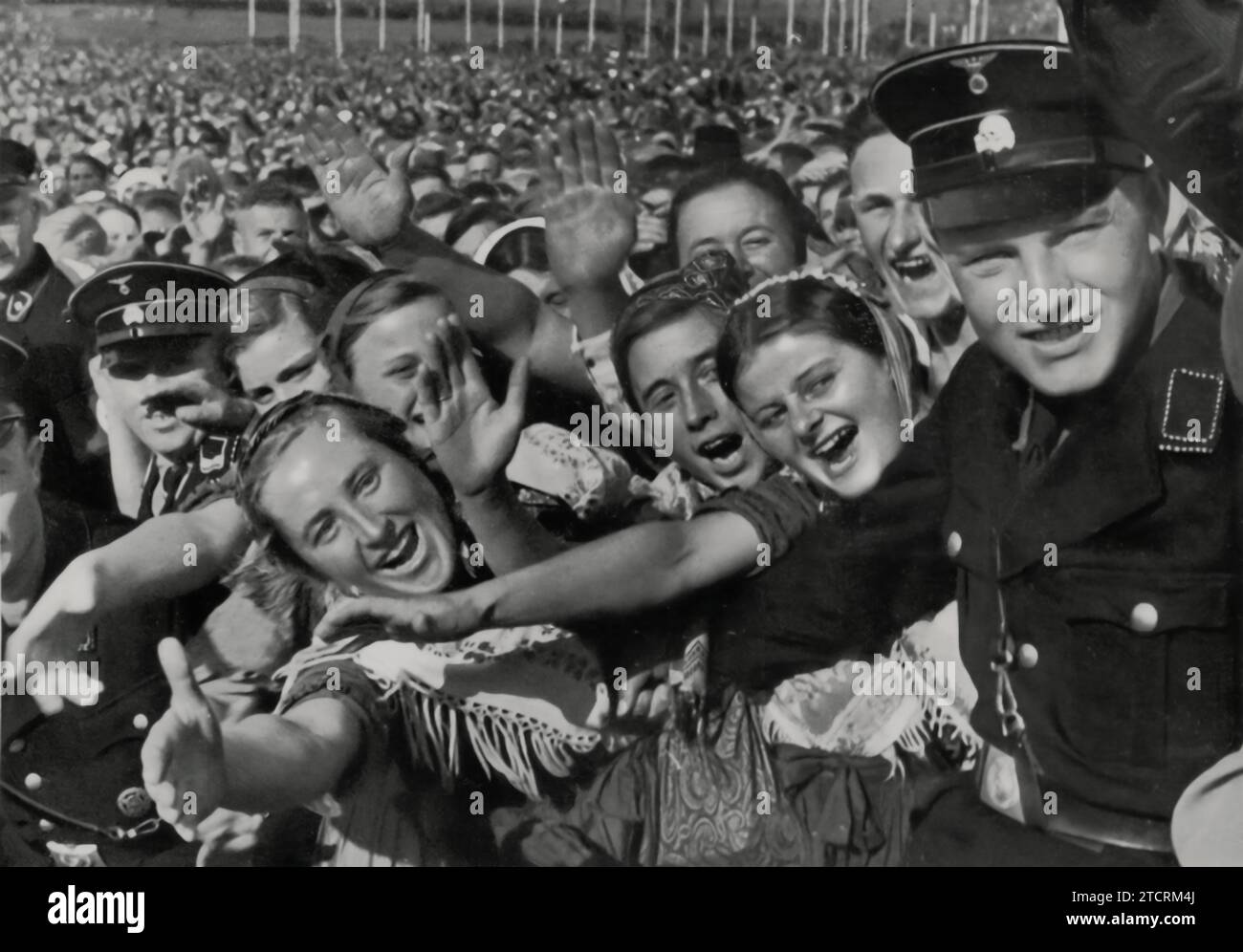 Bei der Buckeberg-Veranstaltung 1935 wird Adolf Hitler von den deutschen Bauern herzlich begrüßt, ein Bild, das die Bemühungen seines Regimes unterstreicht, eine starke Verbindung zur landwirtschaftlichen Gemeinschaft zu erhalten. Die Bauernrezeption Hitlers hebt die Propaganda hervor, die darauf abzielte, ihn als Führer in Verbindung mit allen Bereichen der Gesellschaft, einschließlich der ländlichen Bevölkerung, darzustellen. Diese Interaktionen waren in Nazi-Deutschland bedeutsam, da sie als Symbol für die Einheit zwischen Regierung und Agrarsektor verwendet wurden, ein wichtiger Aspekt der Ideologie des Regimes, der die Bedeutung traditioneller ländlicher Werte betonte. Stockfoto