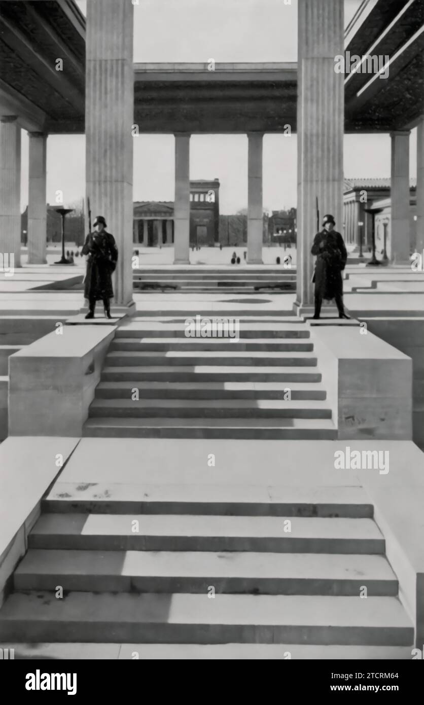 Auf dem Münchner Königsplatz steht die Ewige Garde als feierliche Erinnerung an die NS-Ära, die speziell wegen ihrer historischen und ideologischen Bedeutung ausgewählt wurde. Dieser Ort, der unter der Herrschaft der Nazis in eine Gedenkstätte umgewandelt wurde, war der Ehrung jener gewidmet, die in der gescheiterten Bierhalle Putsch von 1923 starben, einem entscheidenden Ereignis beim Aufstieg der NSDAP. Die Anwesenheit der Ewigen Garde hier diente nicht nur als Hommage an die frühen Märtyrer der Nazi-Bewegung, sondern auch als deutliches Symbol für die Ehrfurcht des Regimes vor seiner Grundgeschichte, die tief in der Münchner Stadtlandschaft verwurzelt ist. Stockfoto