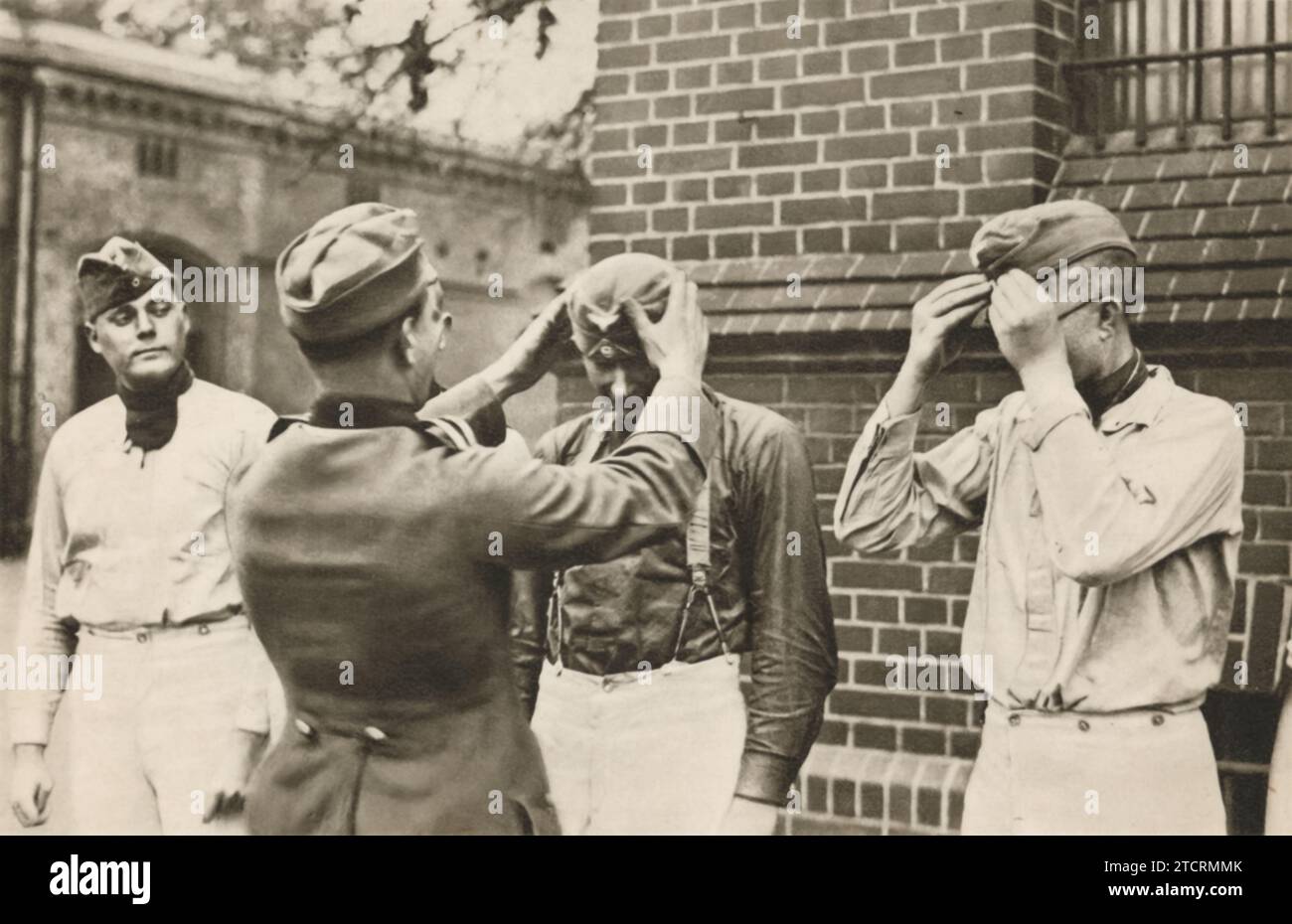 Deutsche Rekruten, die neu in ihrem Militärlager angekommen sind, werden gefangen genommen, wenn sie zum ersten Mal ihre neuen Militärkapseln anschlagen. Dieser Moment markiert einen wichtigen Schritt in ihrem Übergang in das militärische Leben und symbolisiert den Beginn ihrer Reise als Soldaten. Stockfoto