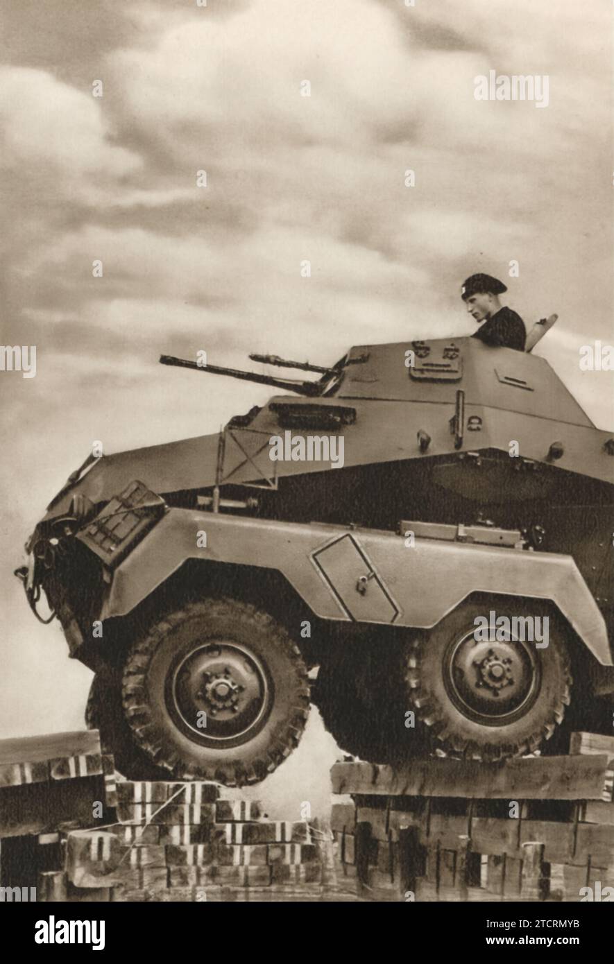 Ein deutsches gepanzertes Fahrzeug, das mühelos eine Barriere überwindet, zeigt die robusten Fähigkeiten dieser Fahrzeuge während des Zweiten Weltkriegs Der Soldat, der das Fahrzeug bedient, ist in der oberen Luke sichtbar, eine Position, die sowohl Sicht als auch Kontrolle bietet. Stockfoto