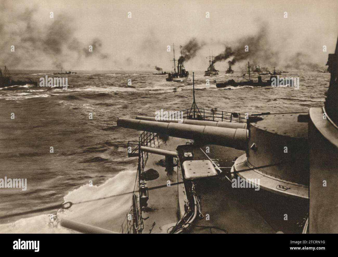 In diesem dramatischen Bild, das an Bord eines Schiffes der deutschen Marine, der Kriegsmarine, aufgenommen wurde, sind mehrere Schiffe mit Rauch zu sehen, der versinkt und weht. Die Szene wird unter der Überschrift „Torpedo Boats Break through for the Attack“ (Torpedoboote brechen für den Angriff durch) aufgenommen, was die Intensität und Wildheit des Seekrieges vermittelt. Dieser Moment zeigt wahrscheinlich eine Schlacht, in der deutsche Torpedoboote, bekannt für ihre Geschwindigkeit und Agilität, ein offensives Manöver durchführen. Stockfoto