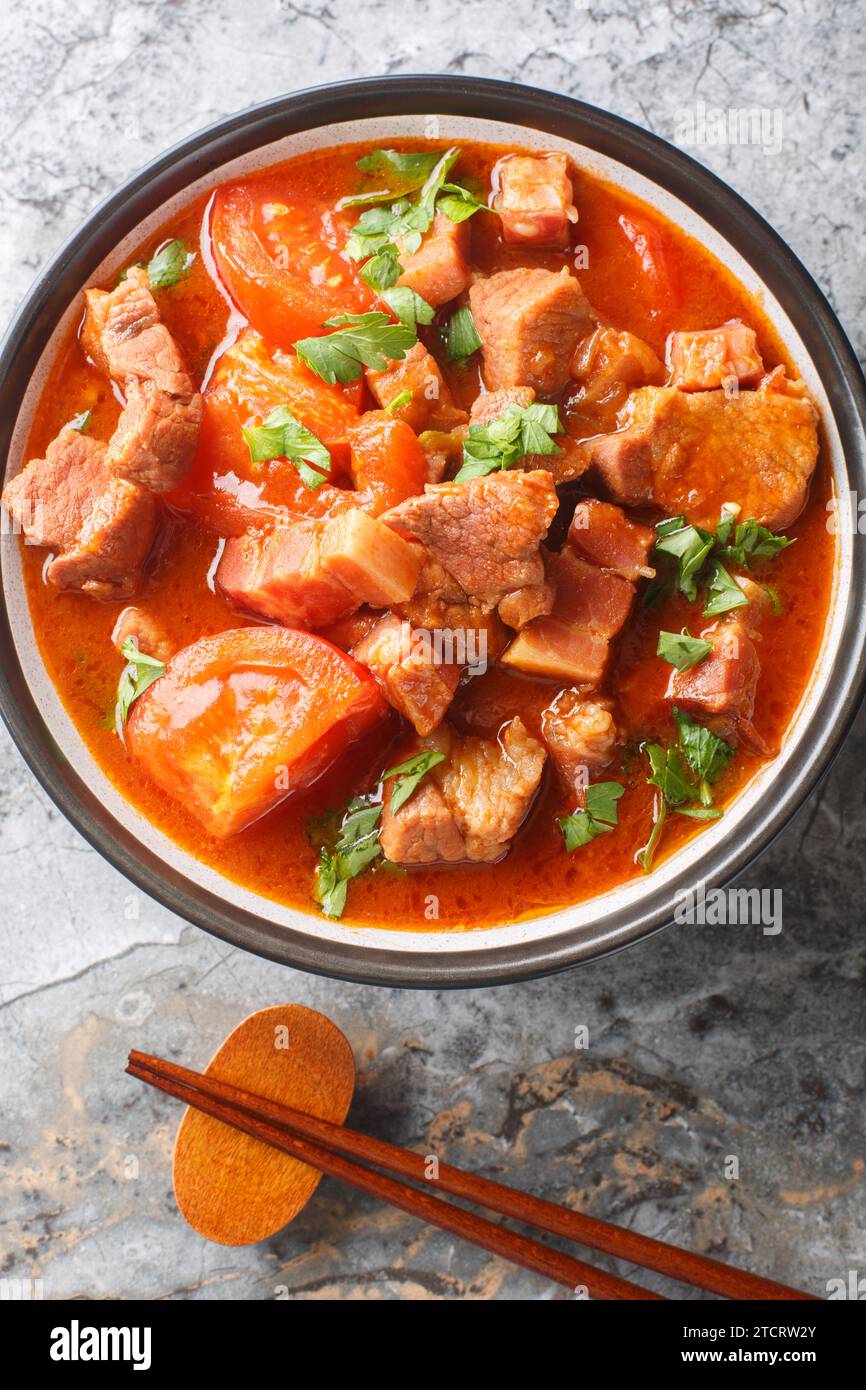 Chinesisches indonesisches Babi Tomat Schweinefleisch gedünstete Tomaten in einer Schüssel auf dem Tisch. Vertikale Draufsicht von oben Stockfoto