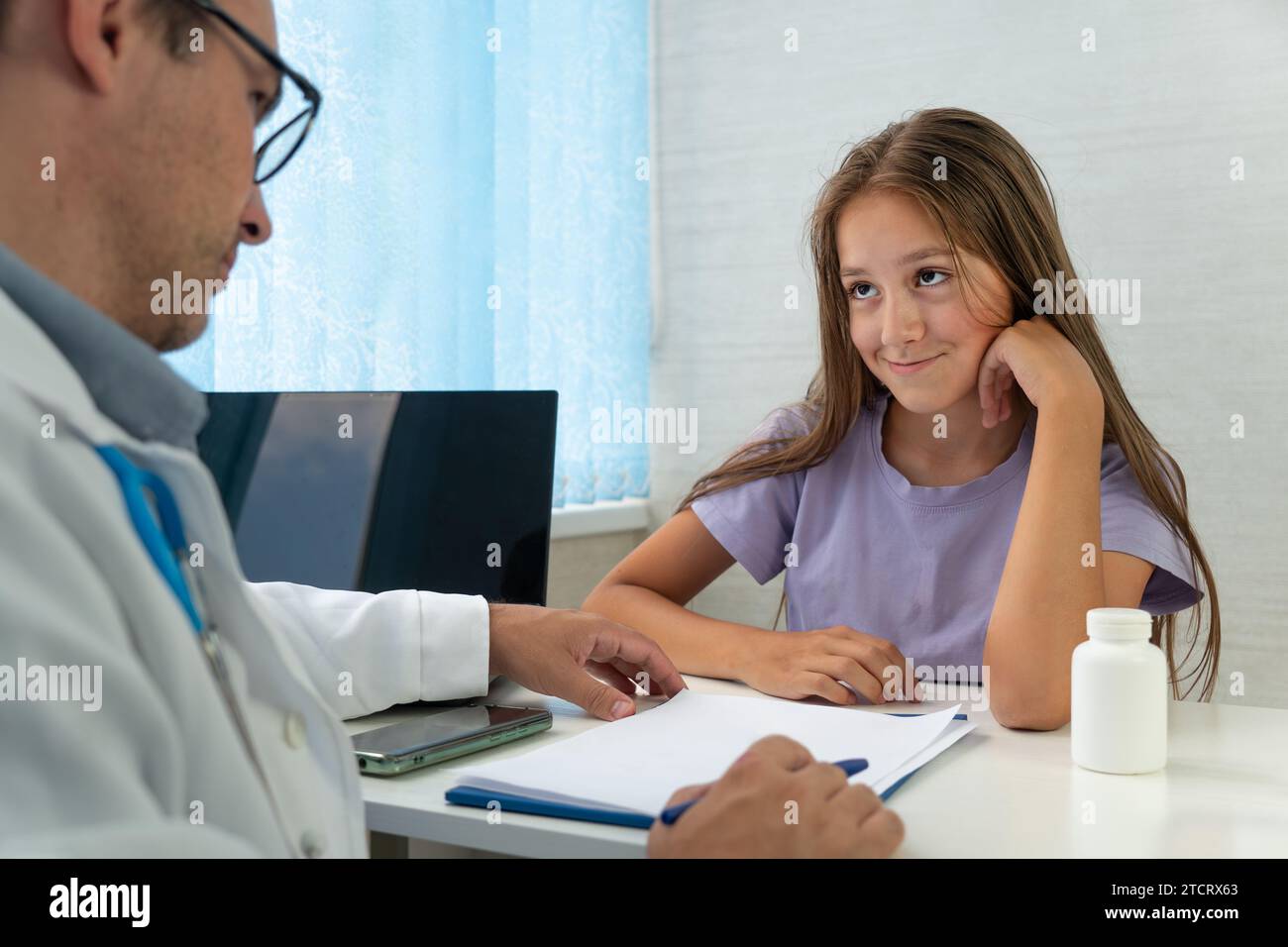 Schulpsychiater-Interviews, berät Kinder. Glückliches Teenagermädchen hört dem Arzt während der ärztlichen Untersuchung in der modernen Klinik zu. Das Mädchen sitzt Stockfoto