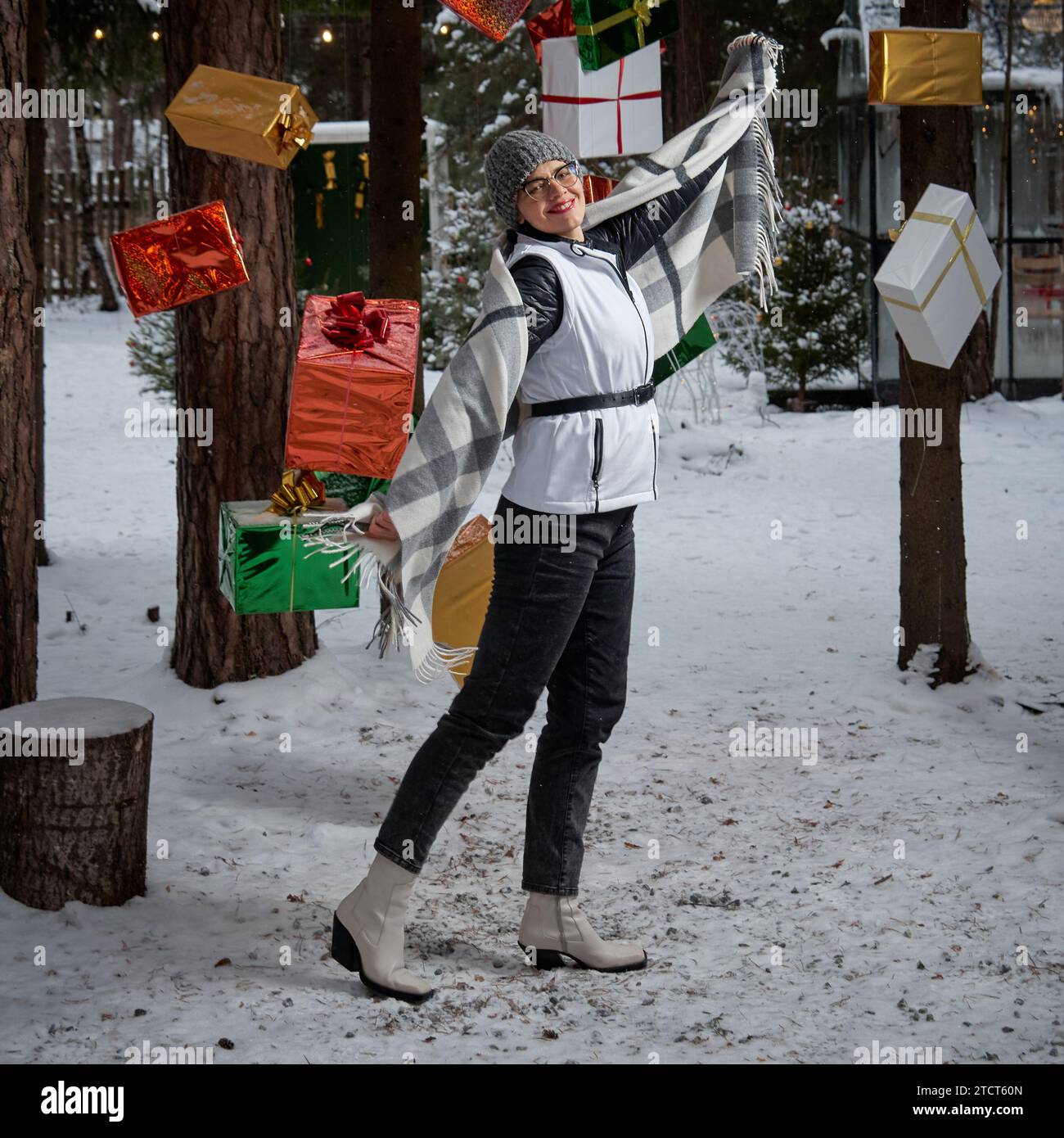 Frau, die zwischen Weihnachtsgeschenken steht, die an Baumzweigen hängen Stockfoto