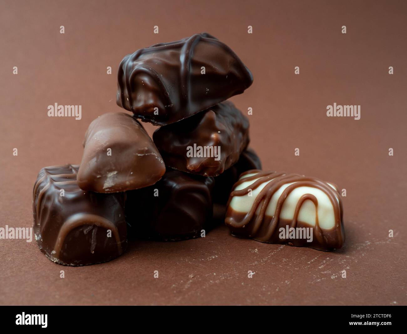 Eine abwechslungsreiche Auswahl an Pralinen auf sattem braunem Hintergrund. Schokoladenbonbons aus der Nähe. Stockfoto