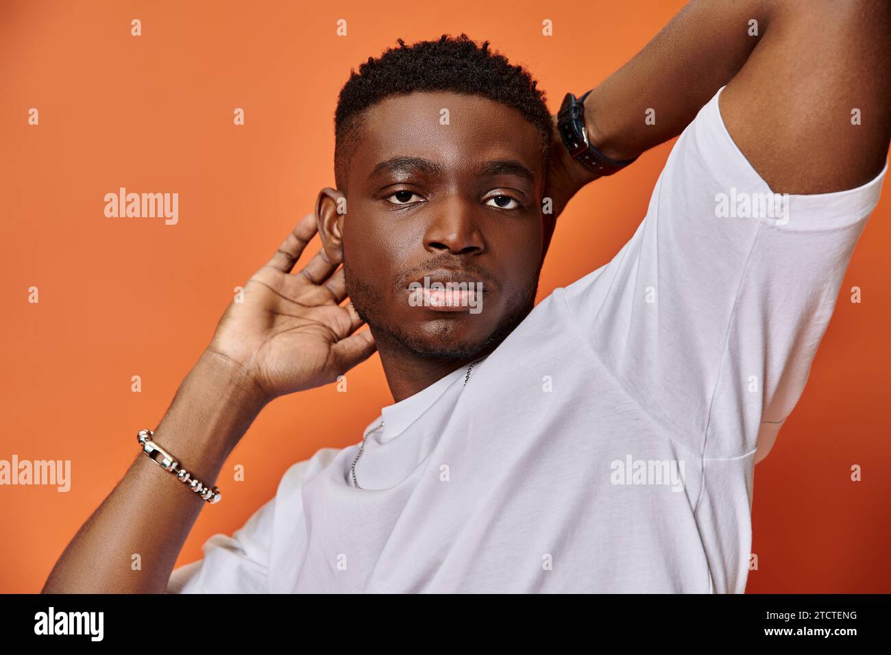 Hübscher, stylischer afroamerikaner in lässigem Outfit auf der Straße vor orangefarbenem Hintergrund, Modekonzept Stockfoto