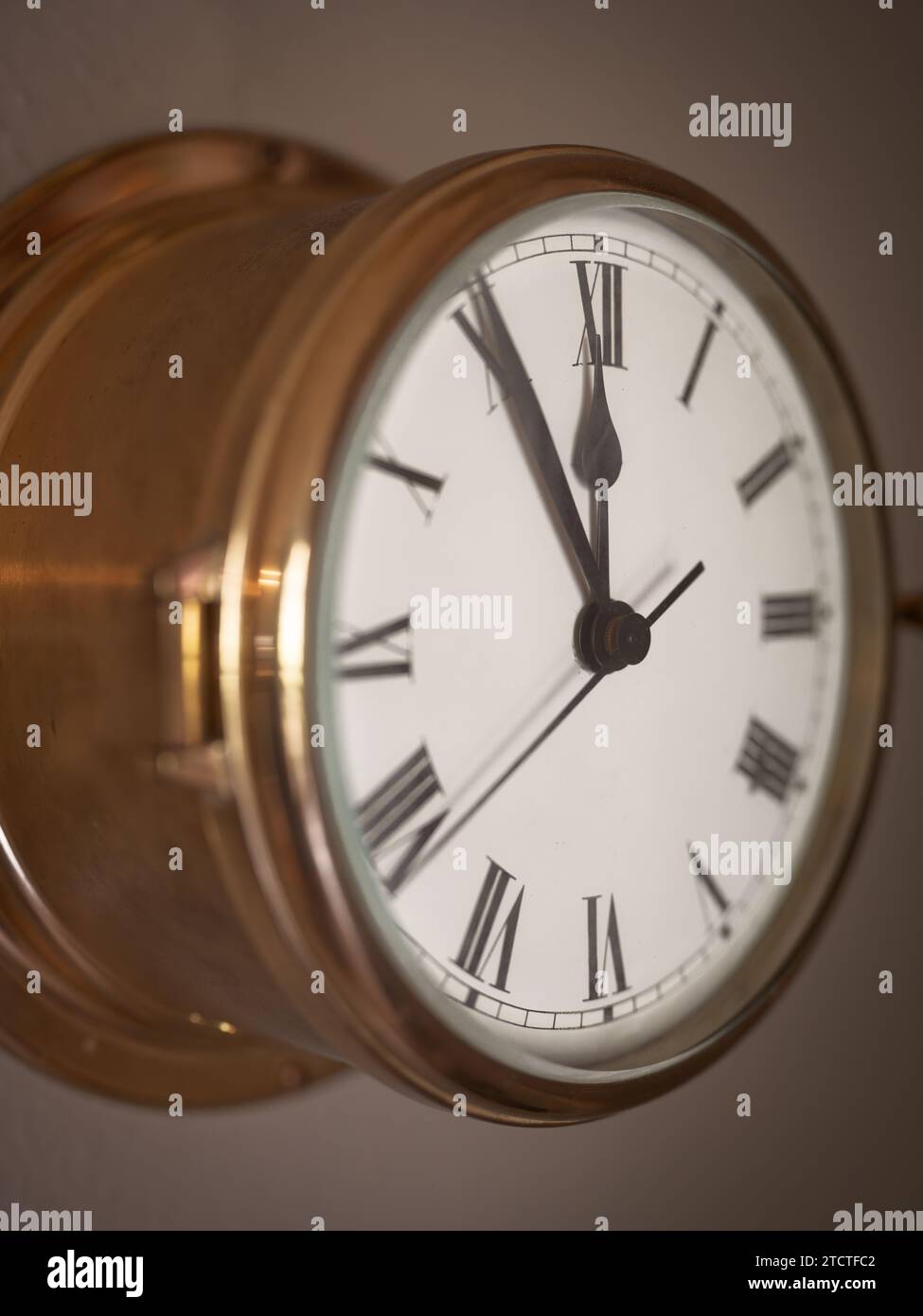 Nahaufnahme einer alten Schiffsuhr mit römischen Zahlen, die sich um Mitternacht nähern. Stockfoto