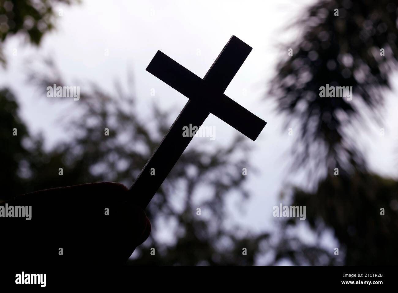 Ein Mann, der ein christliches Kreuz am Himmel hält. Religiöses Symbol des Christentums. Stockfoto