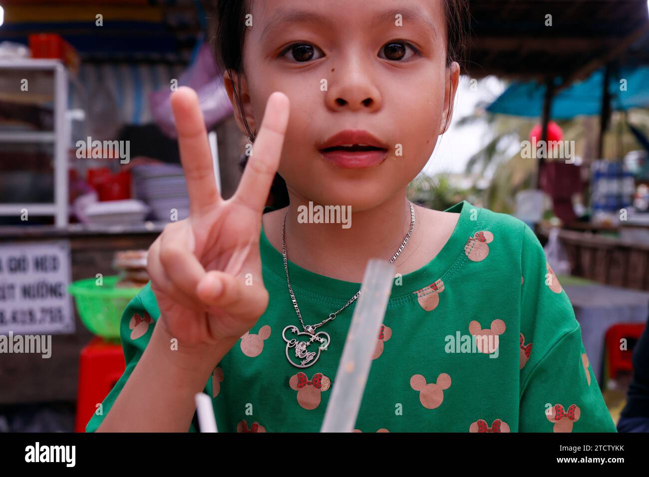 Glückliches asiatisches Mädchen, das das Siegeszeichen macht. Stockfoto