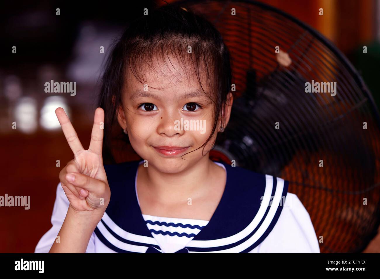 Glückliches asiatisches Mädchen, das das Siegeszeichen macht. Stockfoto