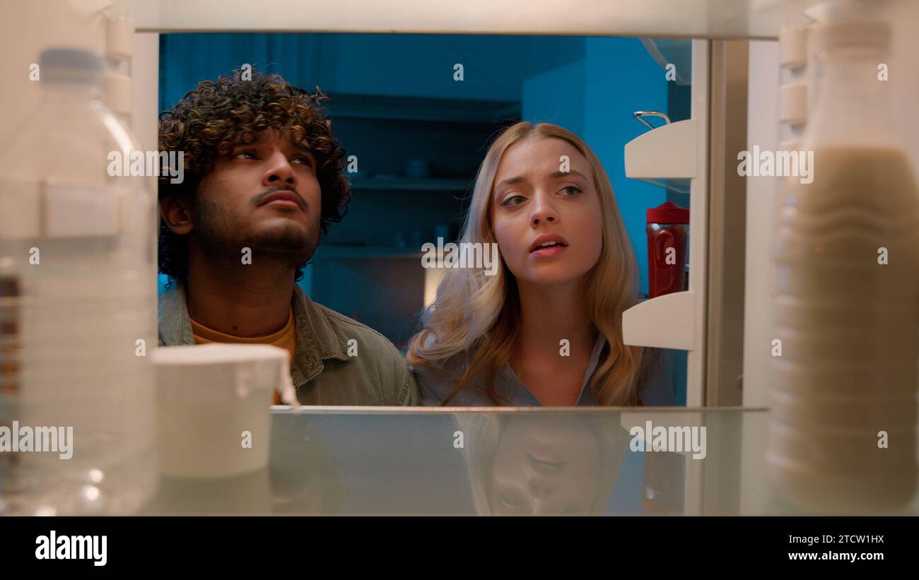 Point of View POV im Kühlschrank Kaukasisches Mädchen Frau Freundin Frau und Araber Mann Indianer Freund Ehemann multirassisches Paar in der Nacht Stockfoto