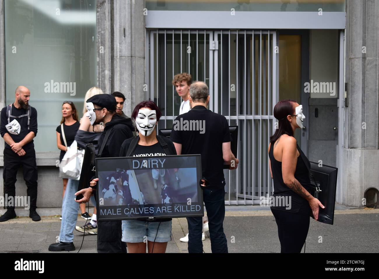 Vegane Demonstranten unter dem Deckmantel "Anonymous", die fernsehbildschirme halten und Bilder von Schlachthöfen freilegen, um Veganismus zu fördern Stockfoto