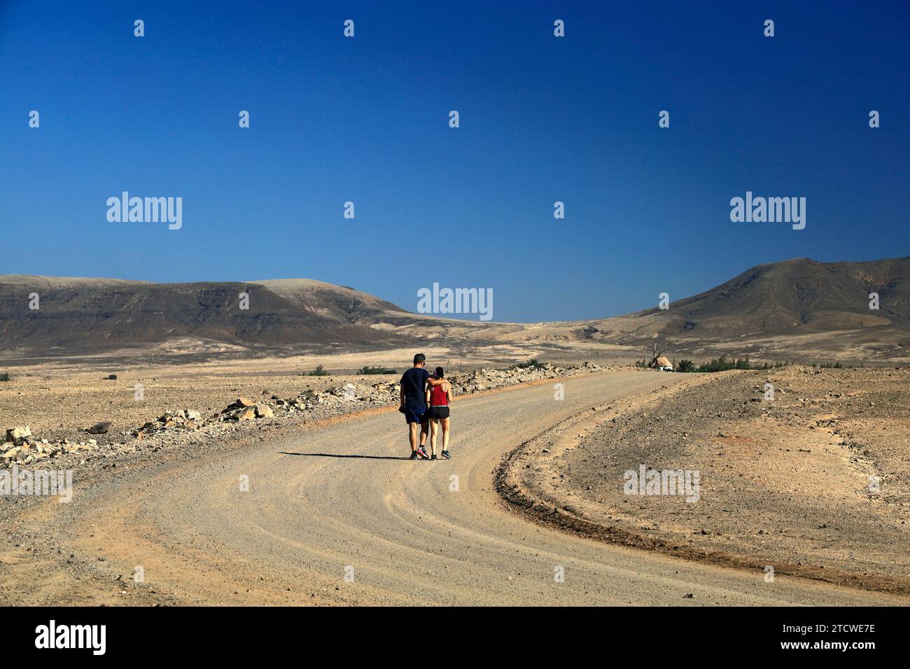 Ein Paar spaziert auf einem staubigen Wanderweg in Richtung El Roque Windmühle, El Cotillo, Fuerteventura, Kanarischen Inseln, Spanien. Stockfoto