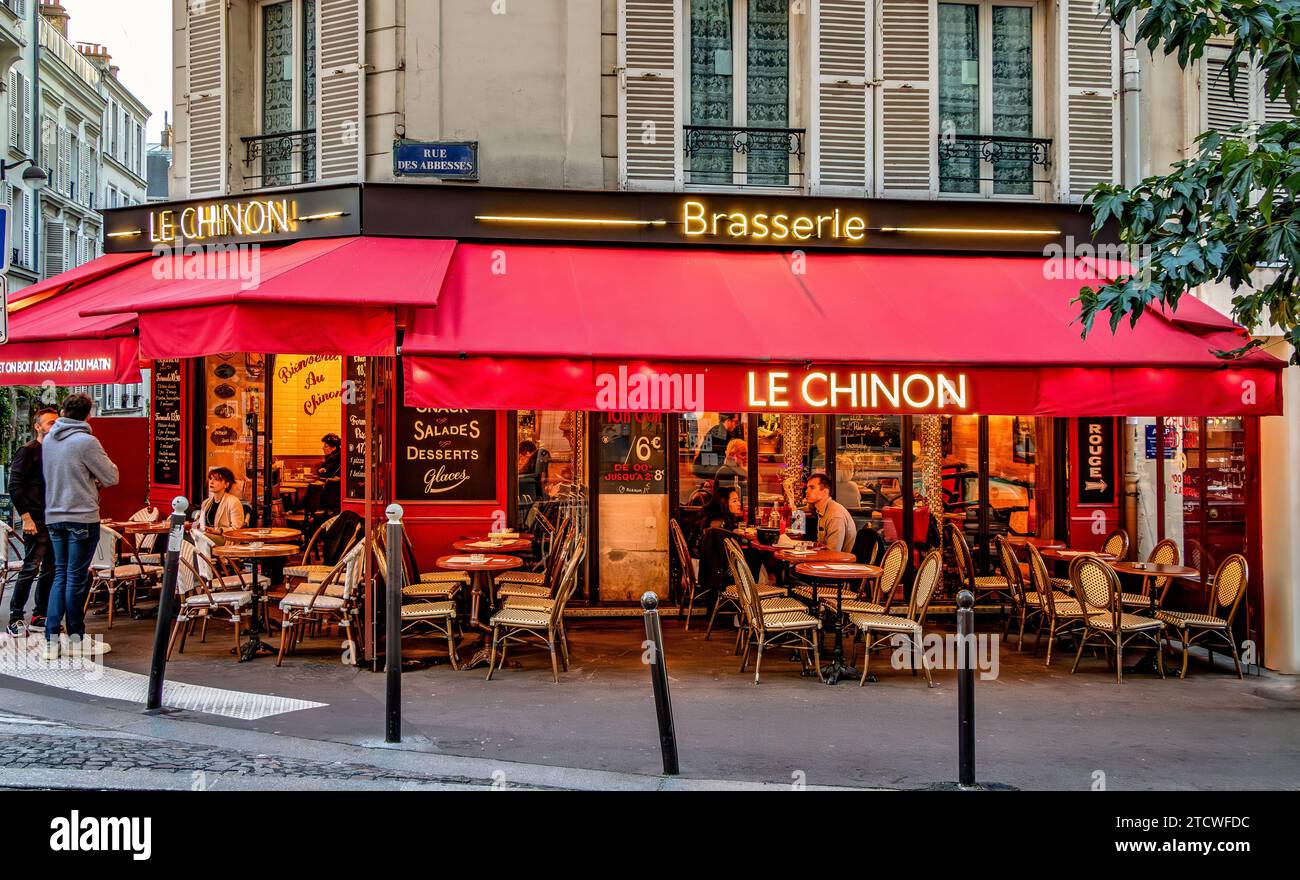 Gäste genießen einen Drink vor Le Chinon, einer Brasserie, einem Café auf der Rue des Abbesses in Montmartre, Paris, Frankreich Stockfoto