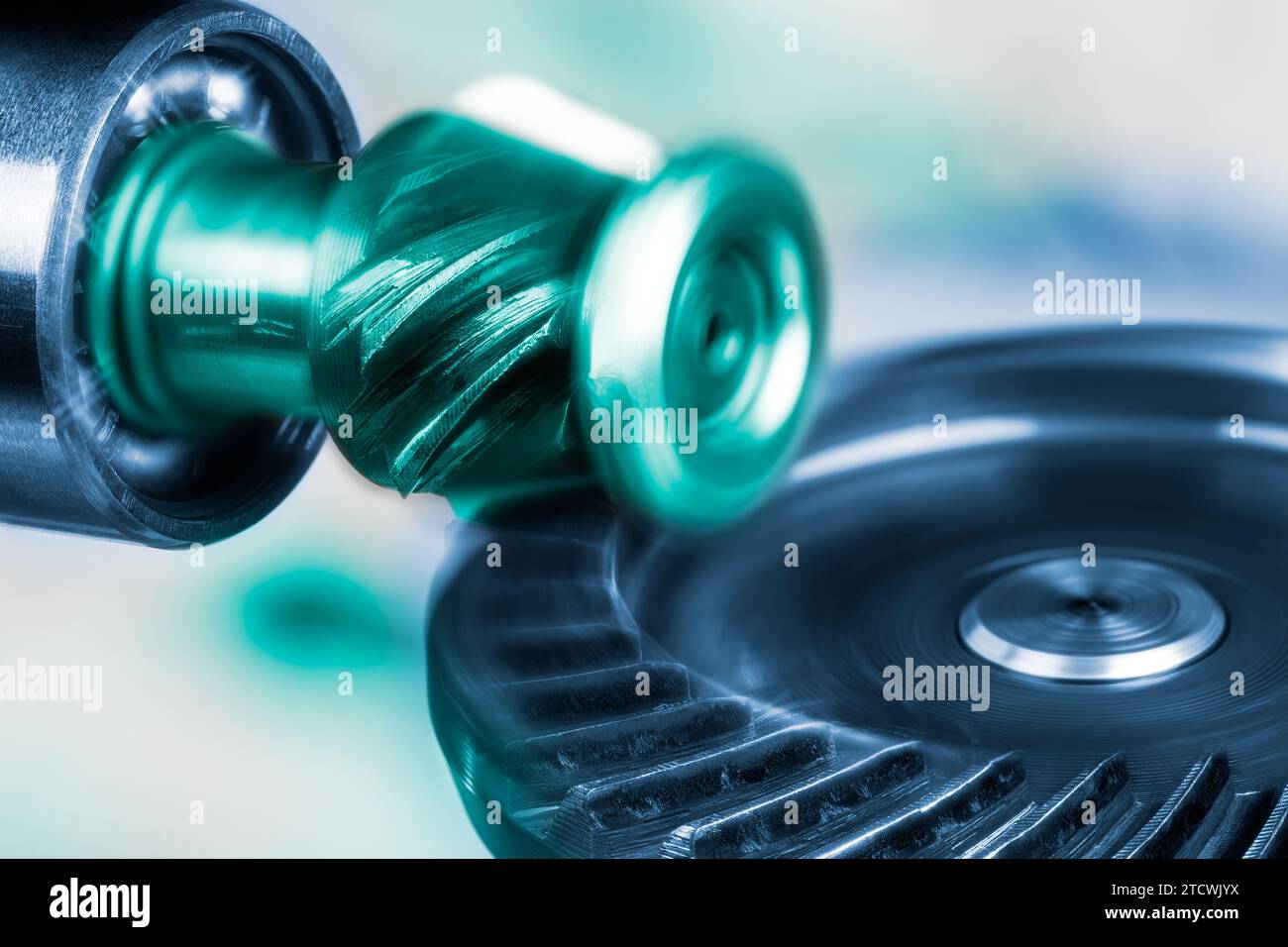 Nahaufnahme drehender, ineinander greifender Metallzahnräder in künstlerischem Blau-Grün-Ton. Schöne Bewegung des perfekt ineinandergreifenden runden Zahnrads und des kleinen Ritzels. Stockfoto