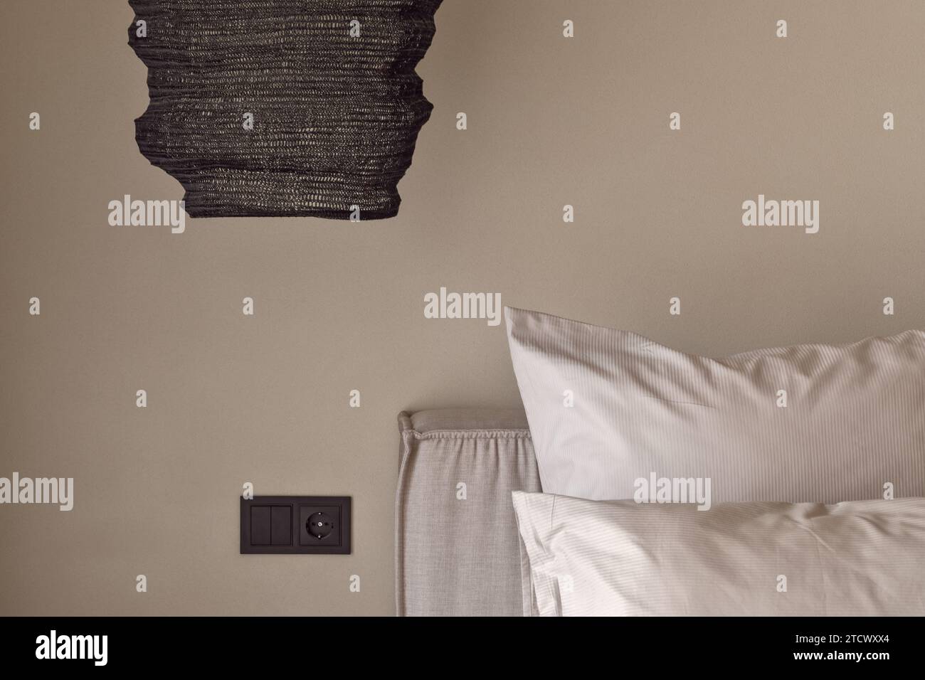 Das Schlafzimmer ist in Erdtönen an der Lehmwand angebracht. Wabi-Sabi-Innenkonzept Stockfoto