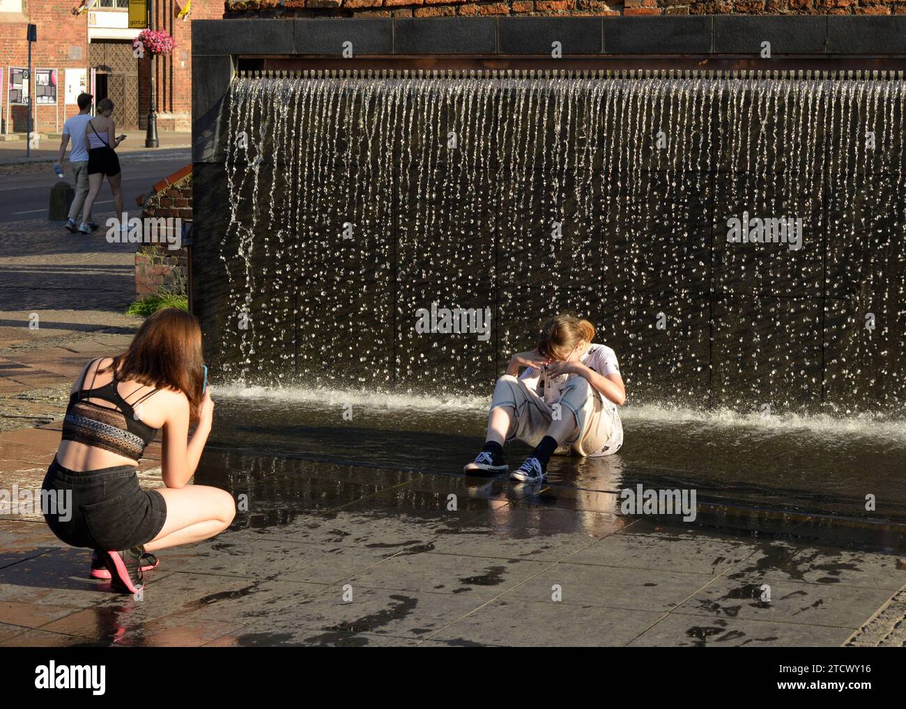 Teenager-Mädchen, das Spaß hat, nass zu werden, in einem Brunnen am Bernsteinmuseum in Danzig, Polen, Europa, EU Stockfoto