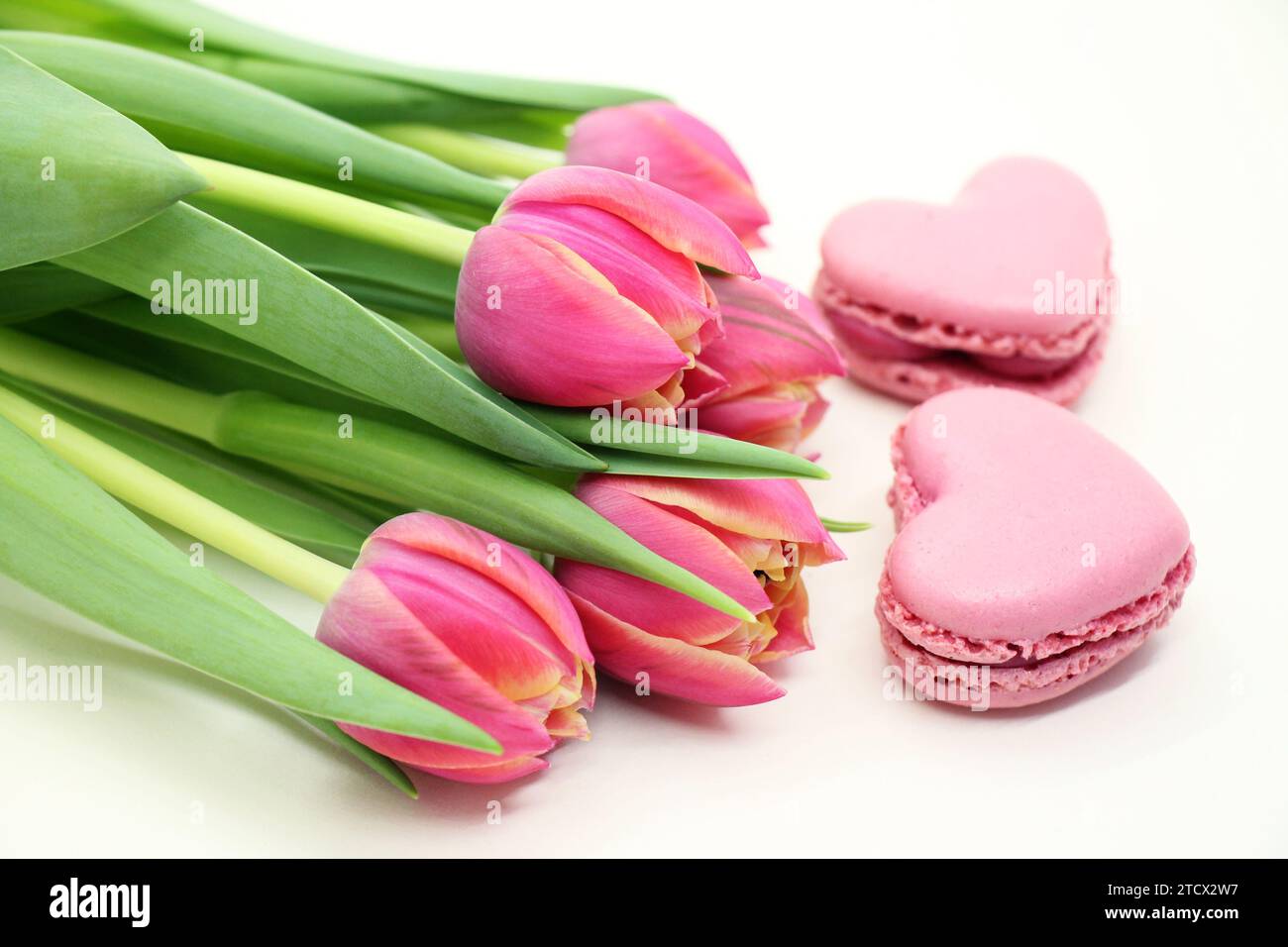 Blumenstrauß frischer rosafarbener Tulpen mit rosa herzförmigen makroons in Nahaufnahme. Stockfoto