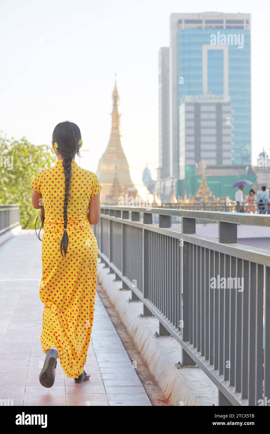Ein Mädchen in einem traditionellen gelben Kleid vor der Sule-Pagode in Yangon, Myanmar. Stockfoto