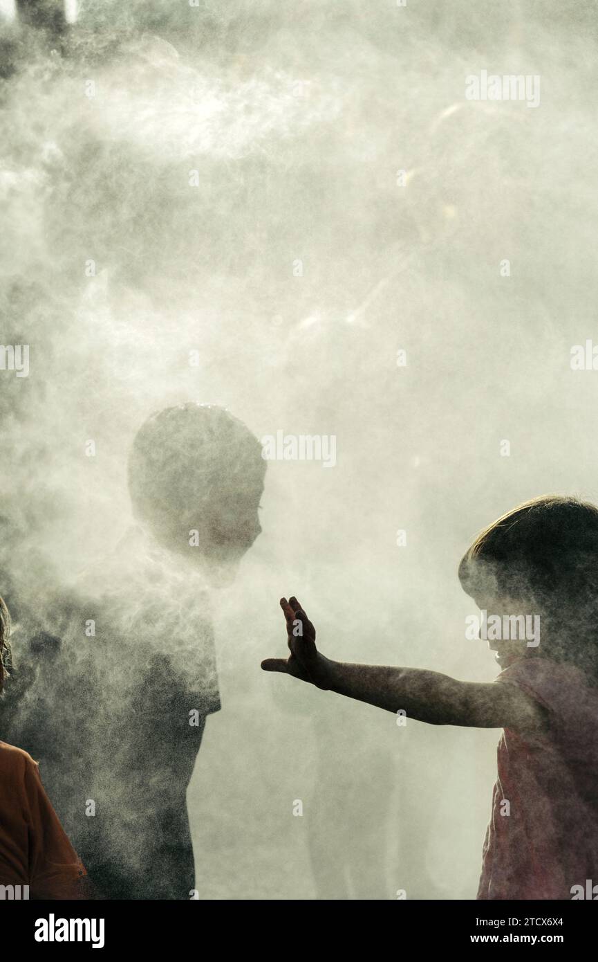 Kinder kühlen sich an heißen Tagen in einer Nebelstation ab, da die globale Erwärmung oder der Klimawandel zu beobachten sind Stockfoto