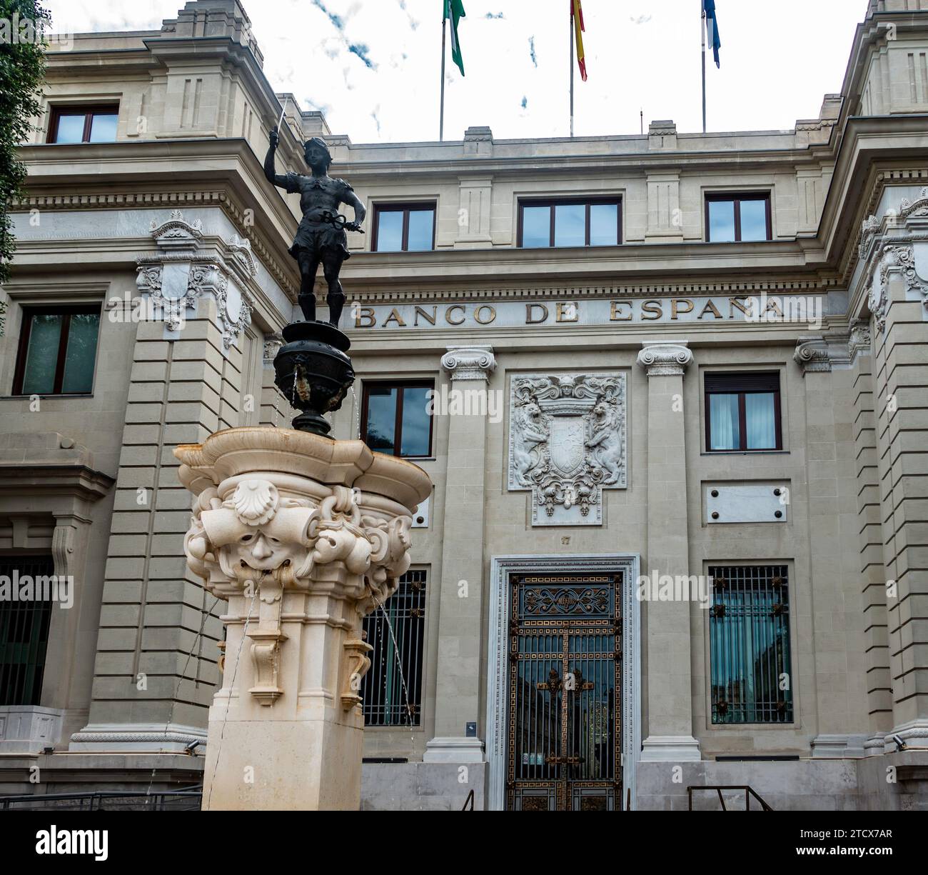 Historische Architektur der Banco de Españain Sevilla, Spanien, mit kunstvollen Skulpturen und Fahnen. Stockfoto