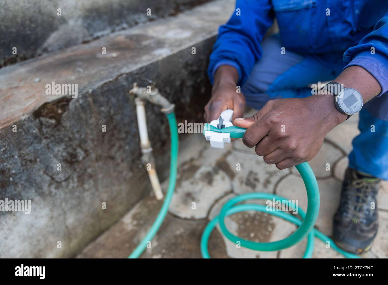 Der erste Schuss der Hände eines afrikanischen Klempners, der ein Rohr schneidet. Stockfoto